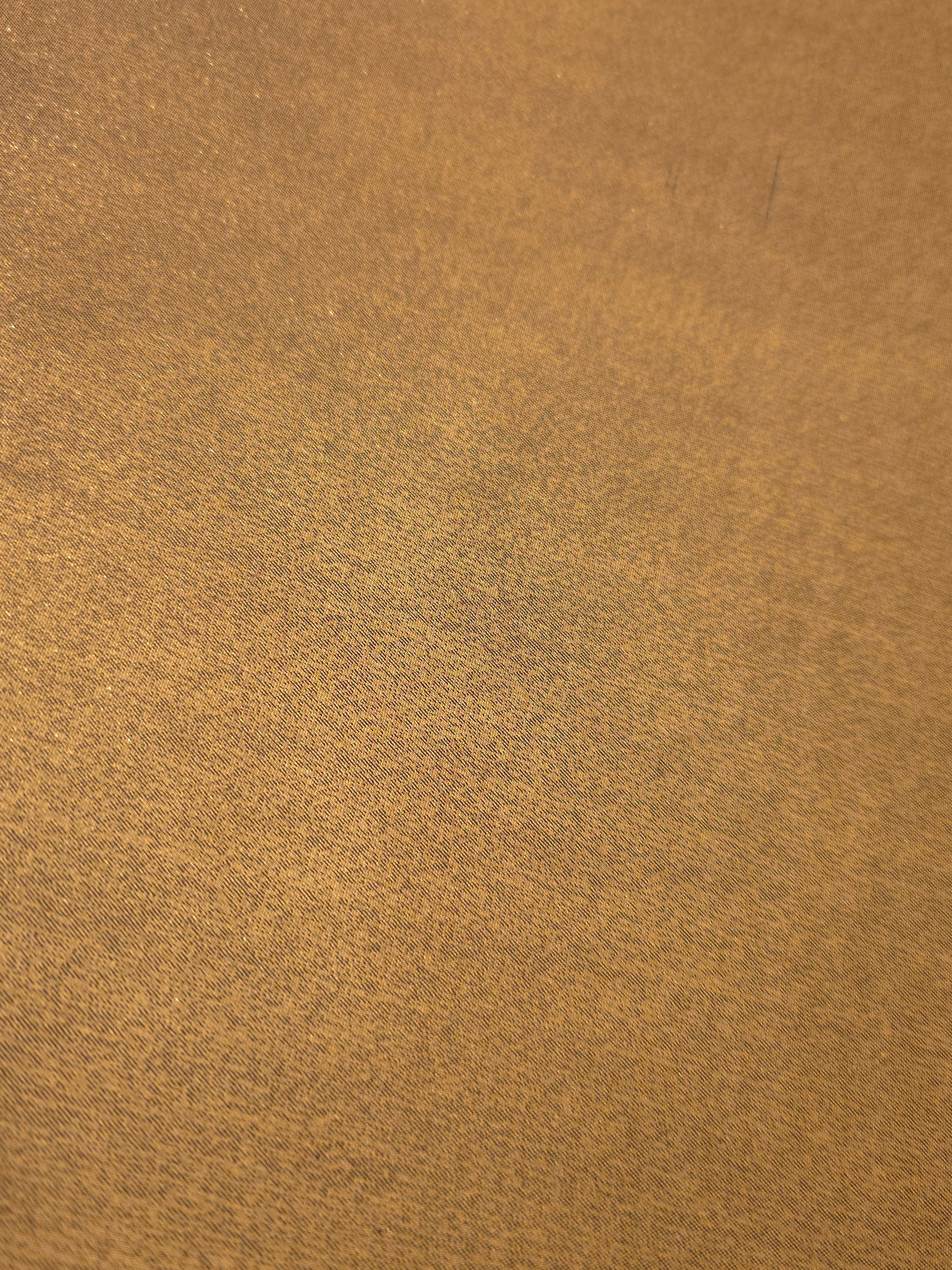 Antique brass fold detail view of liquid metallic shimmer chiffon fabric, highlighting fluid folds and reflective surface