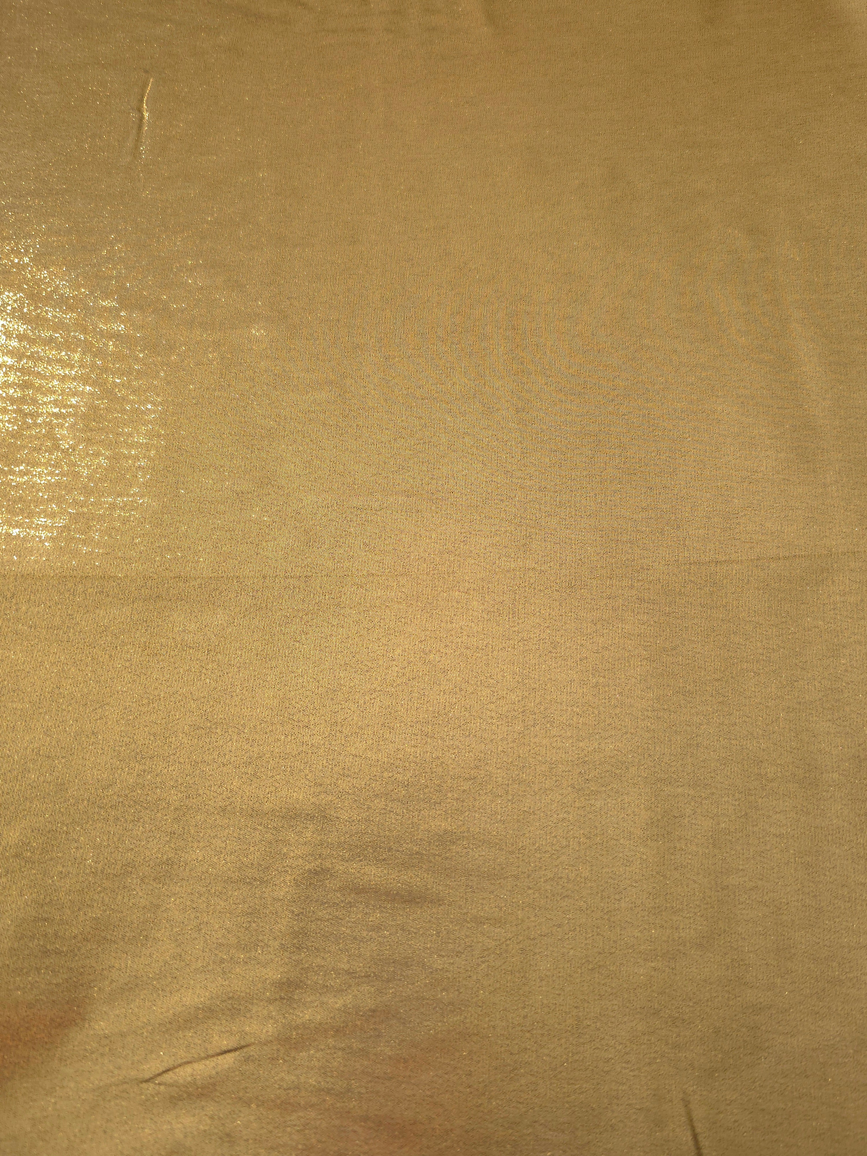 Antique gold fabric overview view of liquid metallic shimmer chiffon fabric, highlighting fluid folds and reflective surface