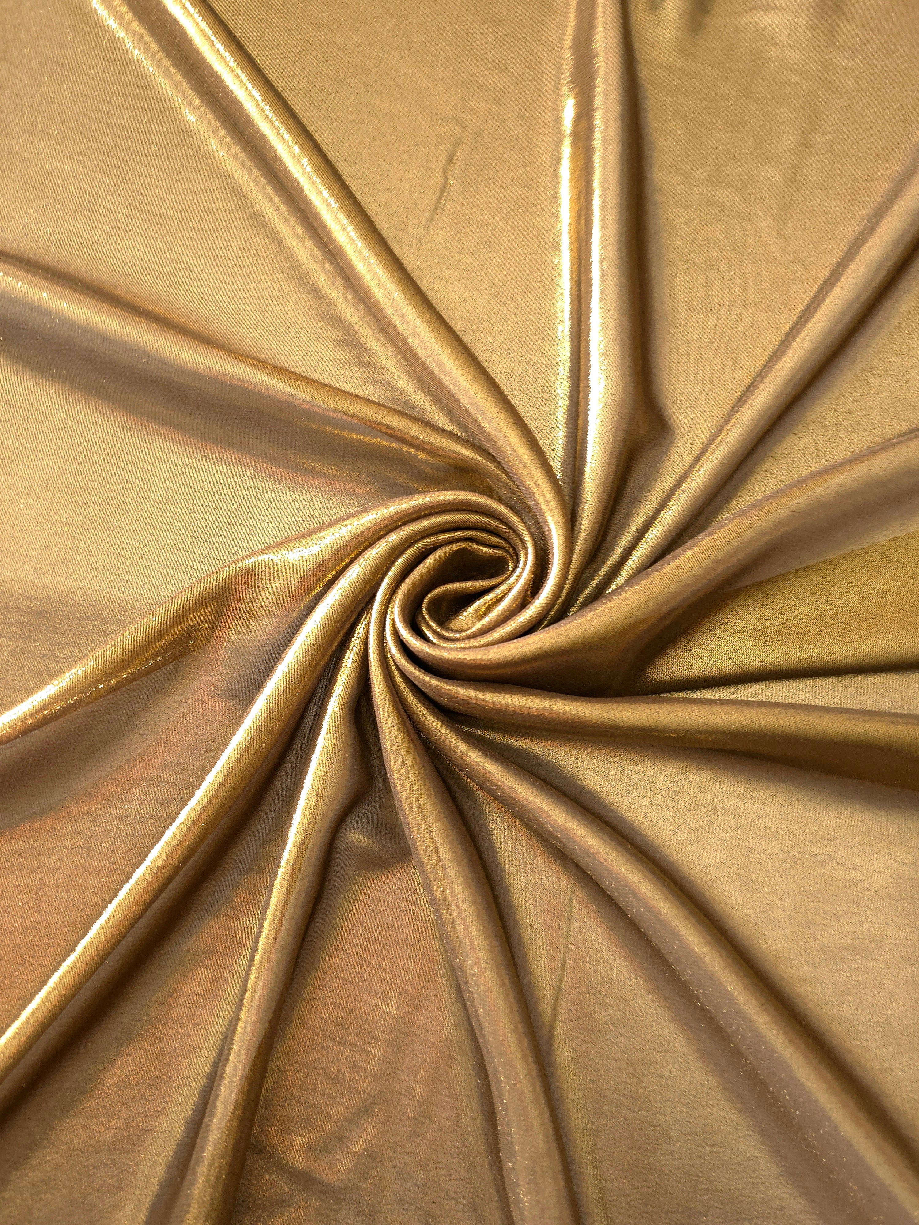 Antique gold shimmer close up view of liquid metallic shimmer chiffon fabric, highlighting fluid folds and reflective surface