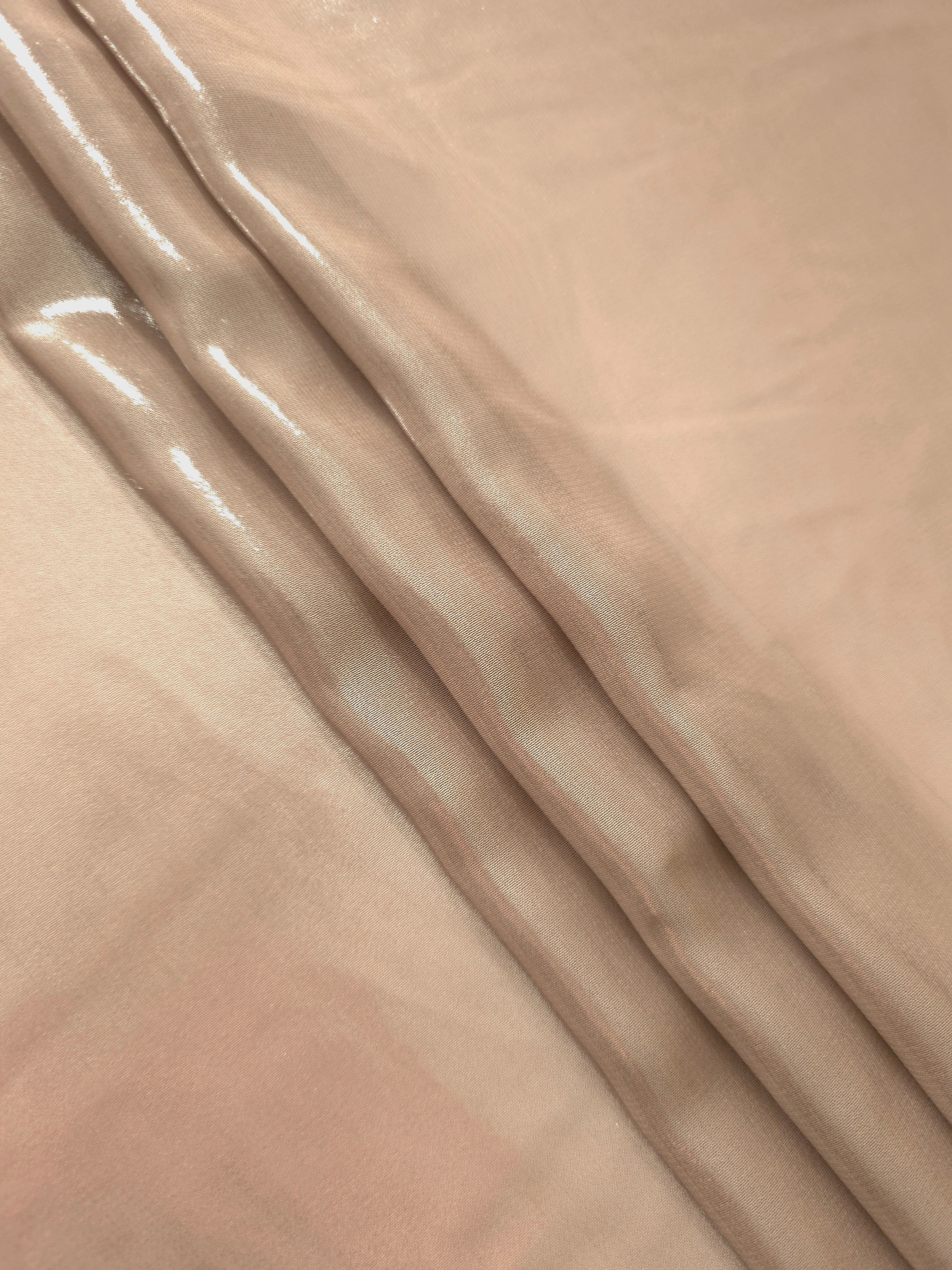 Champagne beige flowing folds view of liquid metallic shimmer chiffon fabric, highlighting fluid folds and reflective surface