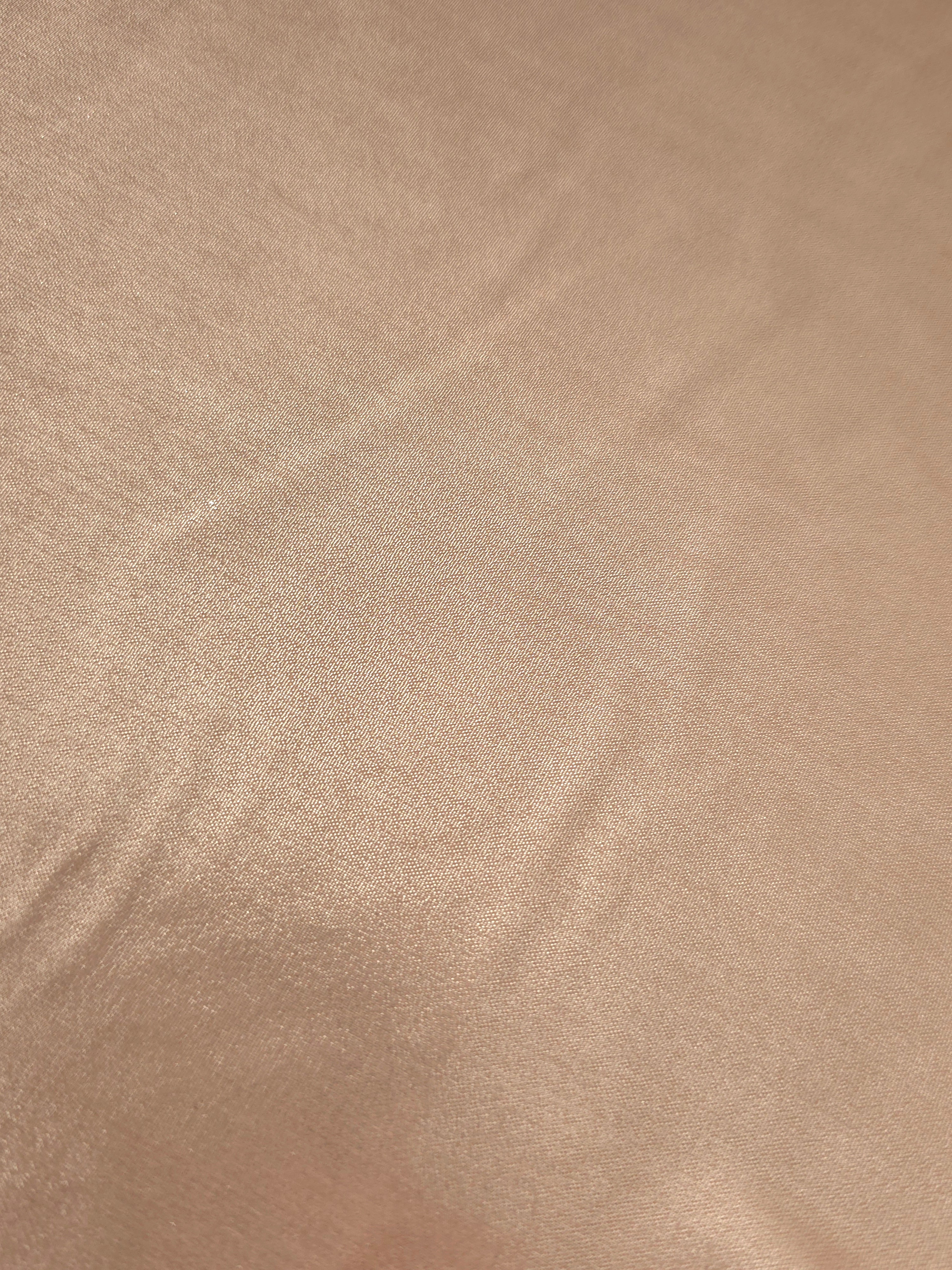 Champagne beige fold detail view of liquid metallic shimmer chiffon fabric, highlighting fluid folds and reflective surface