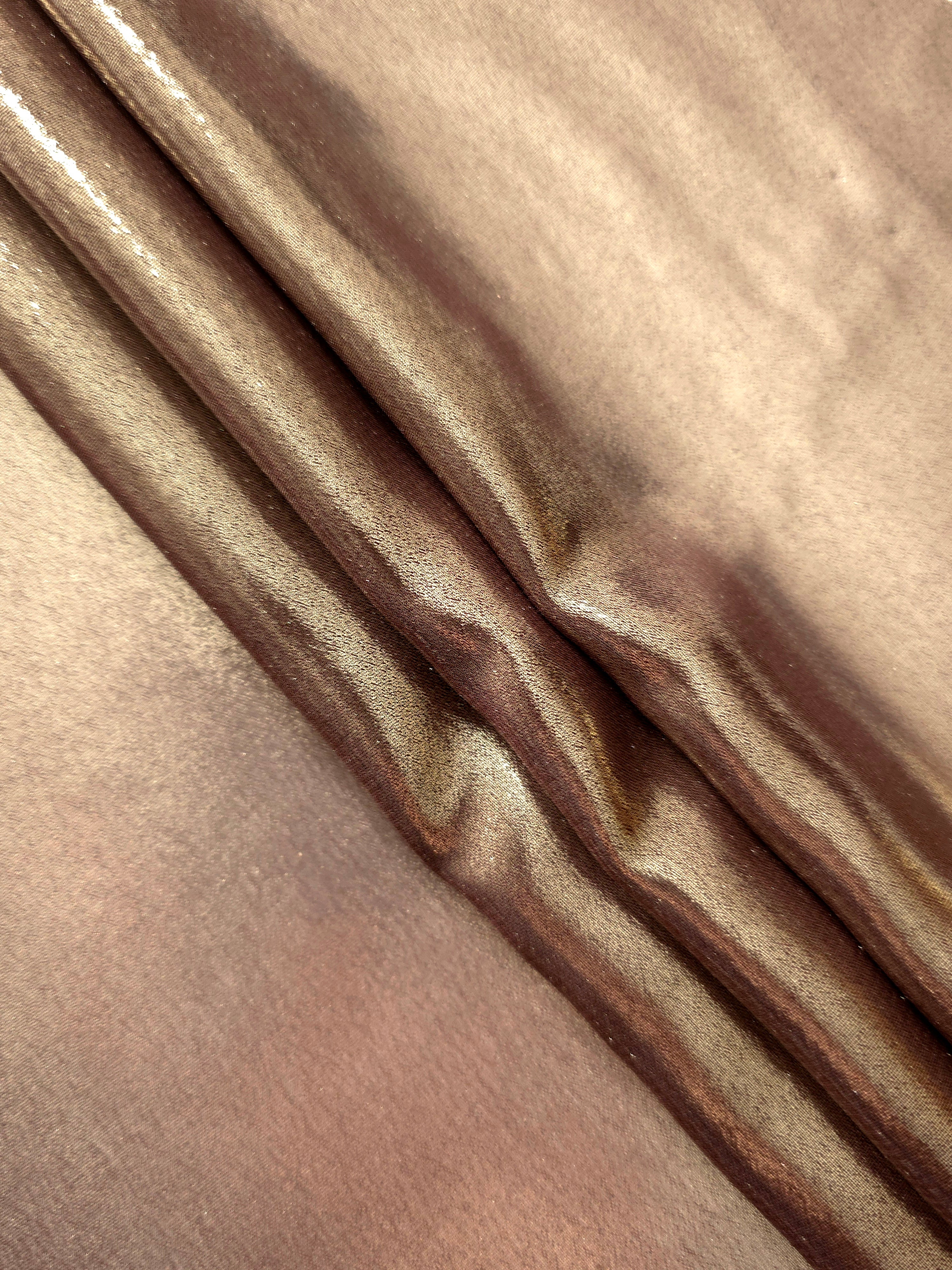 Copper glow flowing folds view of liquid metallic shimmer chiffon fabric, highlighting fluid folds and reflective surface