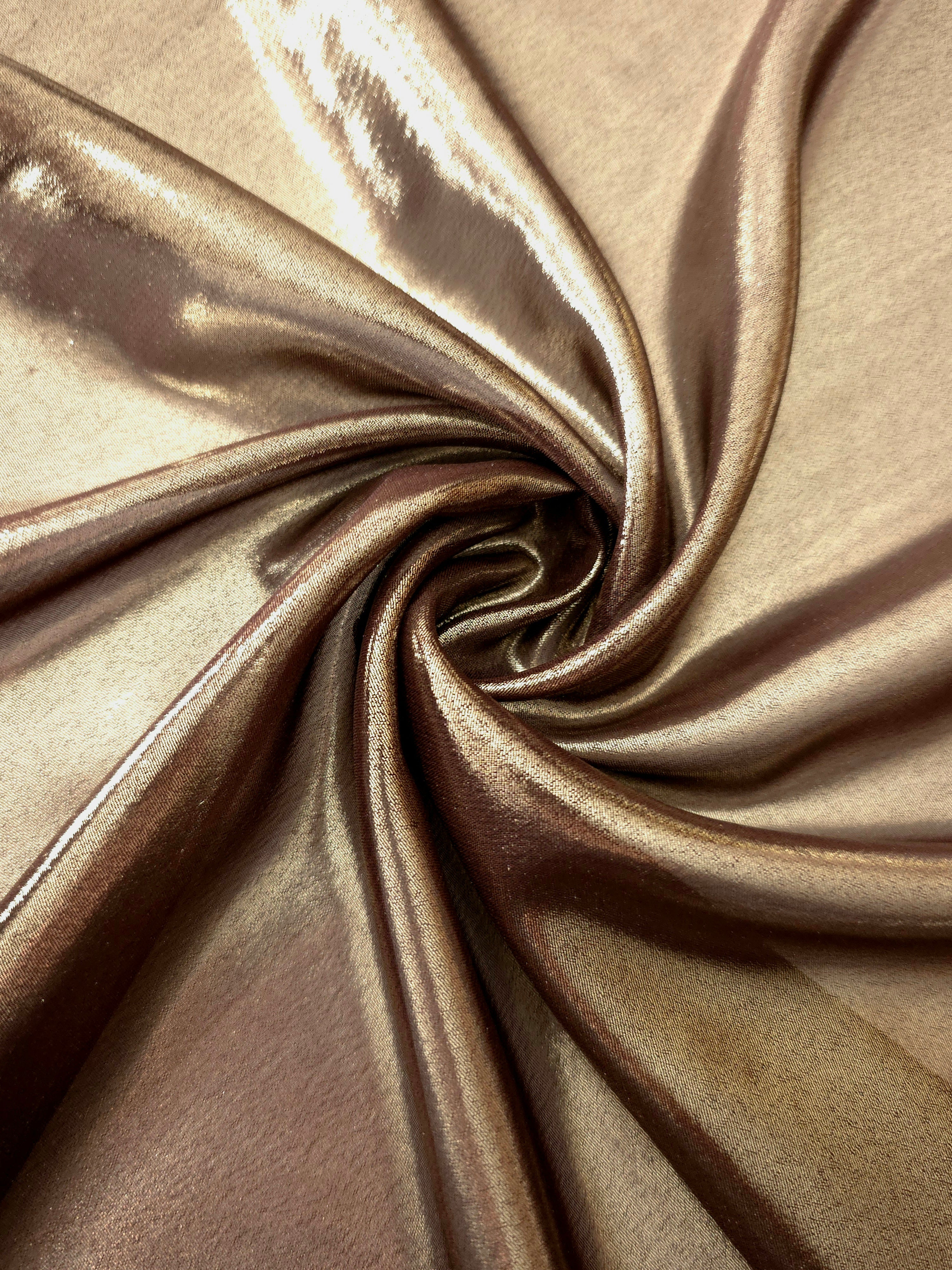 Copper glow shimmer close up view of liquid metallic shimmer chiffon fabric, highlighting fluid folds and reflective surface