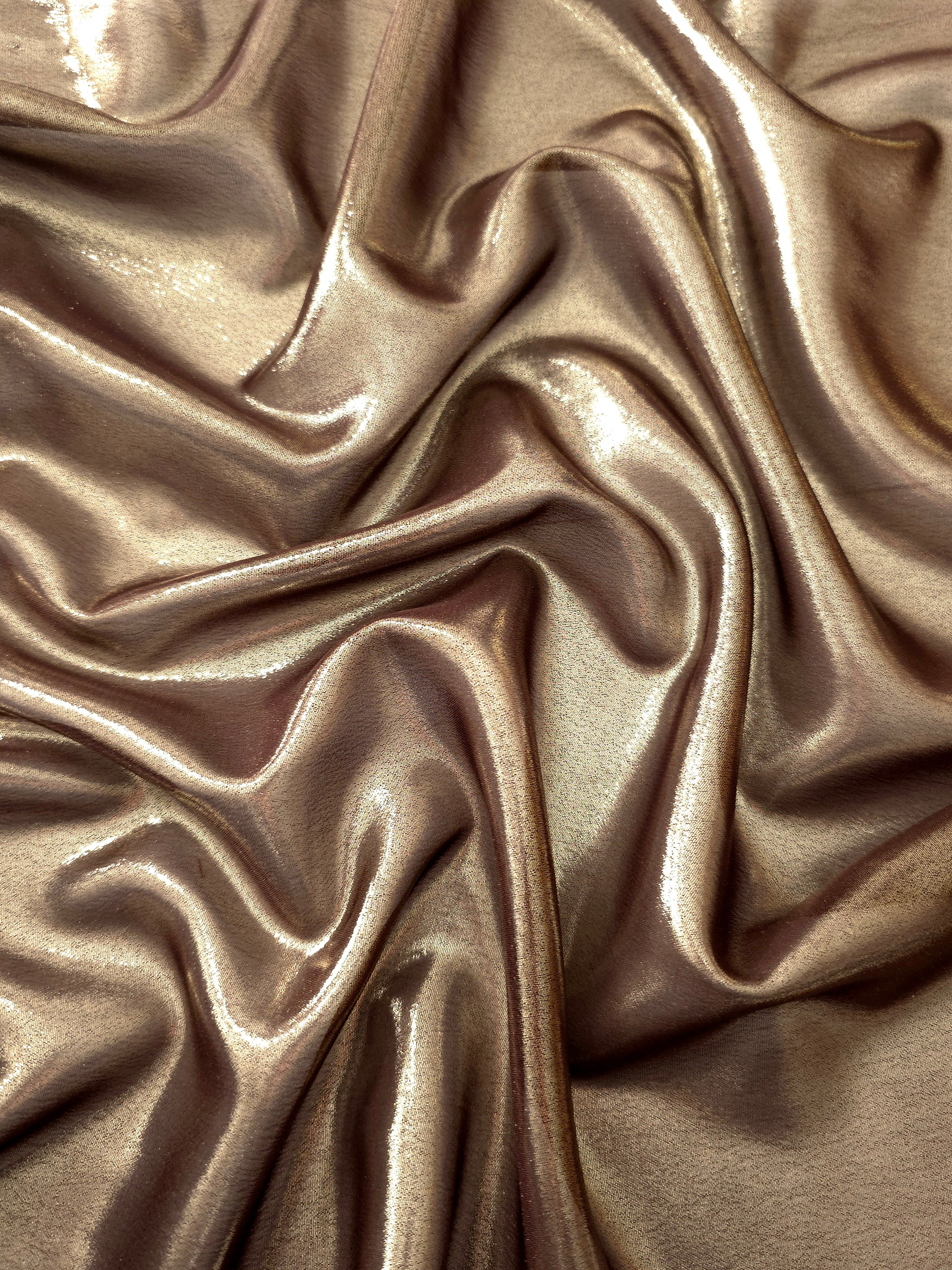 Copper glow surface detail view of liquid metallic shimmer chiffon fabric, highlighting fluid folds and reflective surface