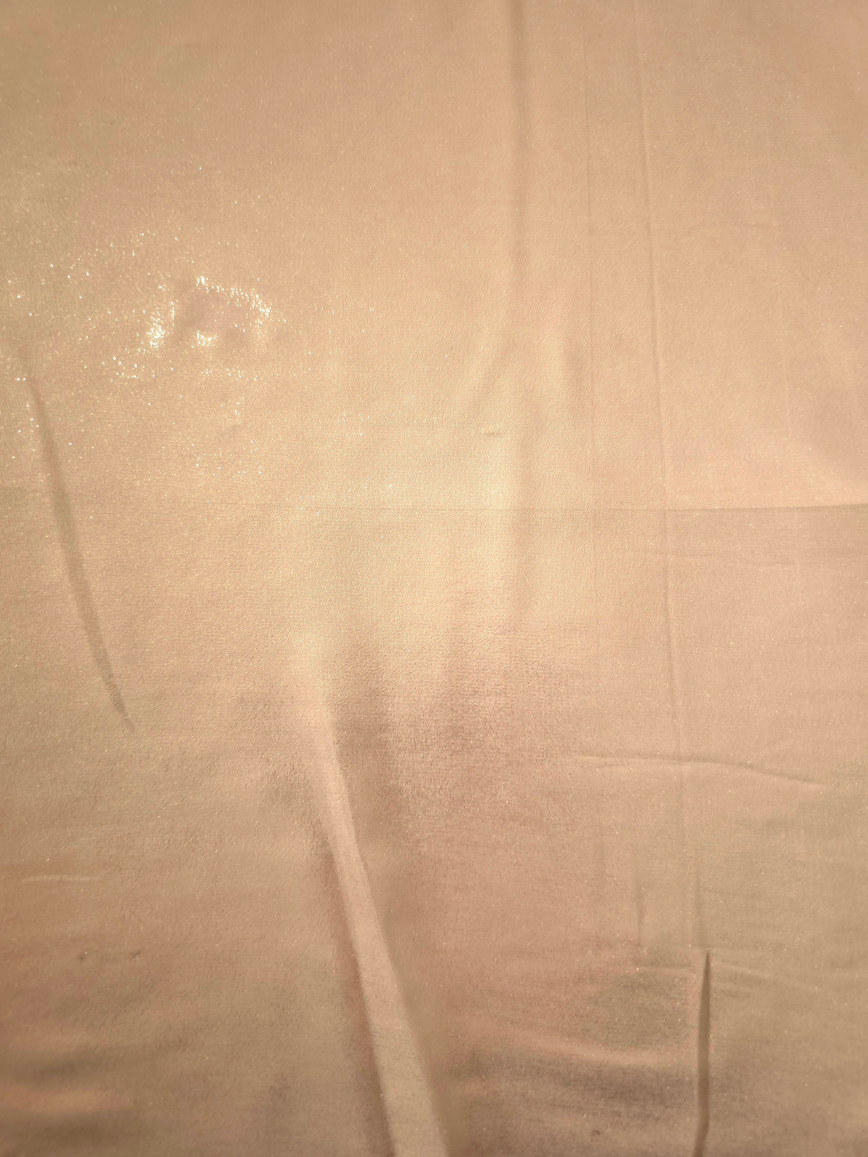 Cream gold fabric overview view of liquid metallic shimmer chiffon fabric, highlighting fluid folds and reflective surface