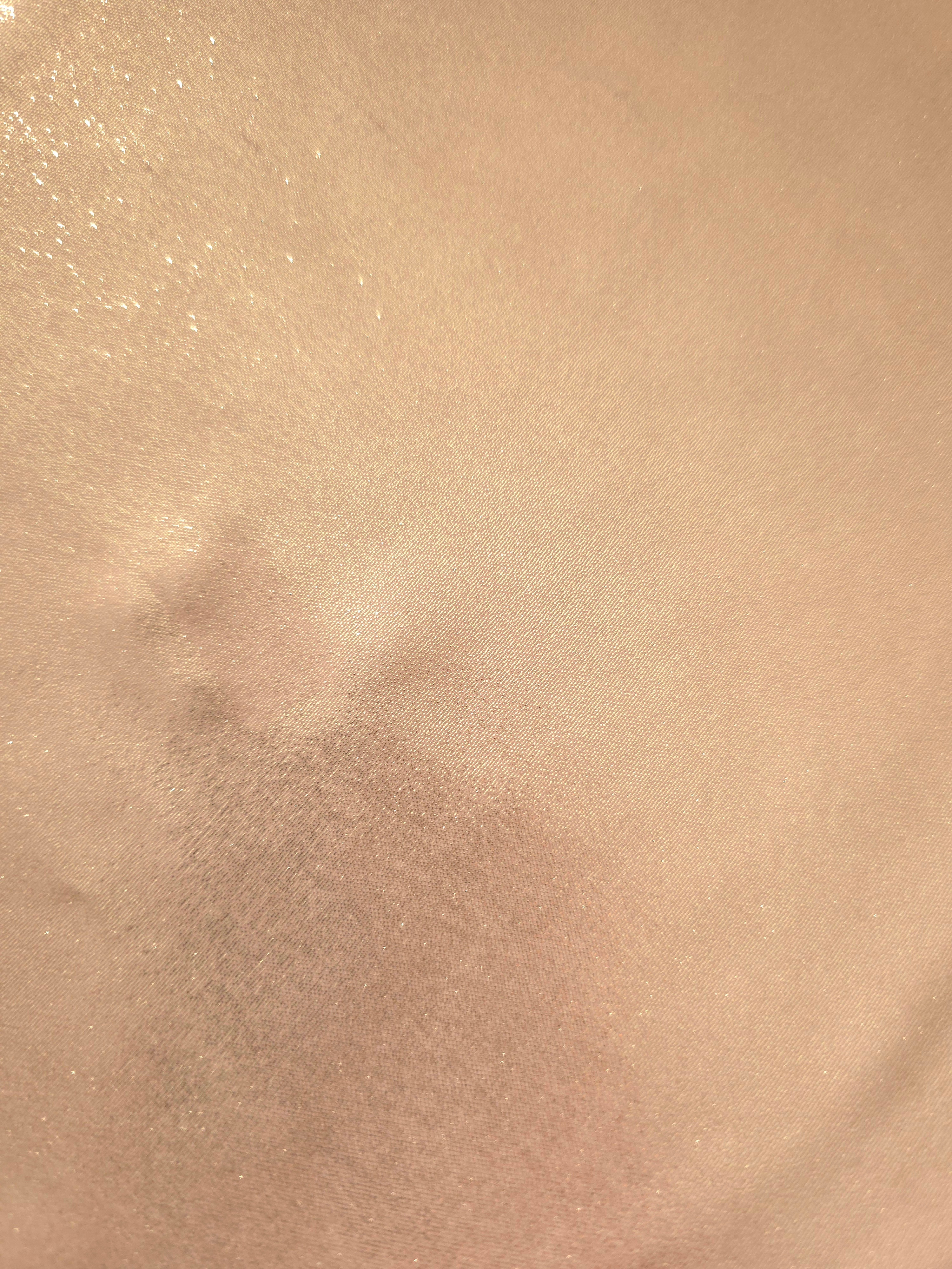 Cream gold fold detail view of liquid metallic shimmer chiffon fabric, highlighting fluid folds and reflective surface