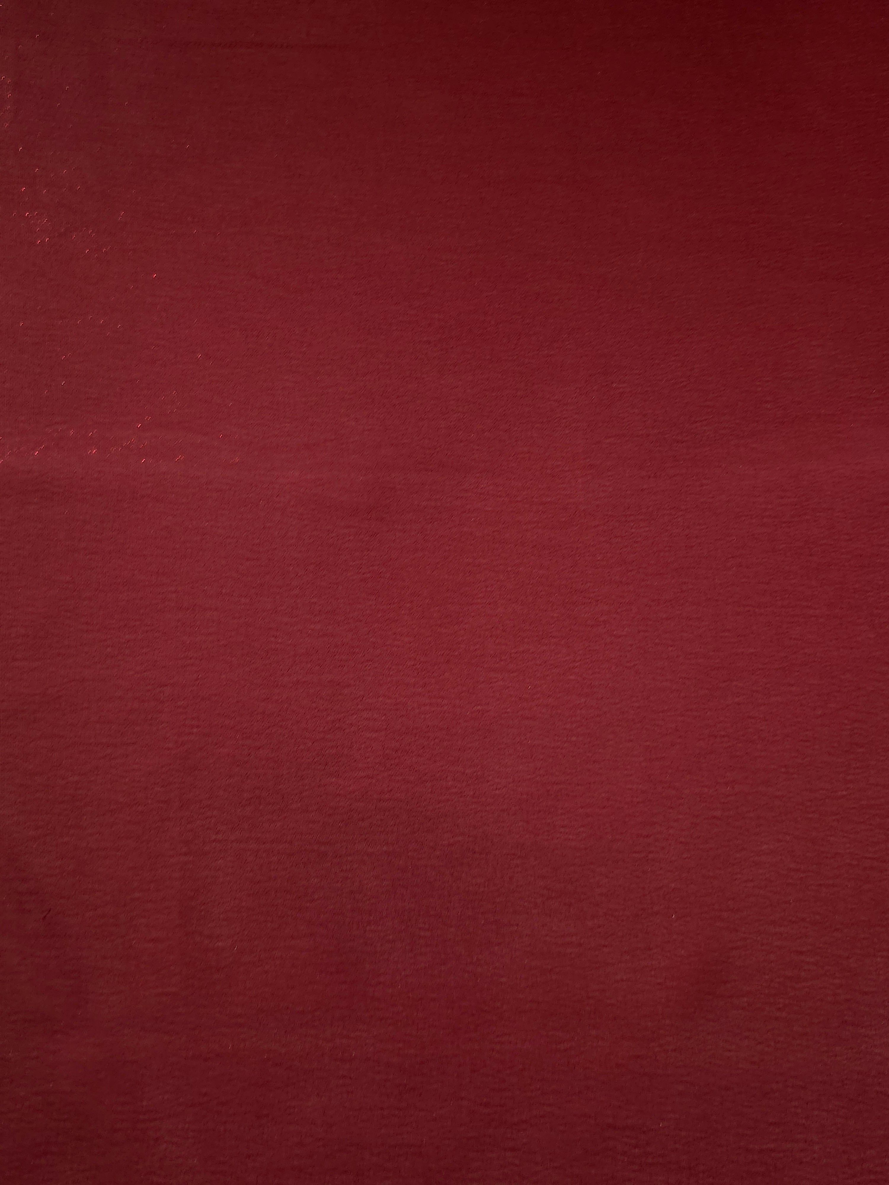 Deep burgundy fabric overview of liquid metallic shimmer chiffon fabric, showing lightweight reflective fabric texture and drape