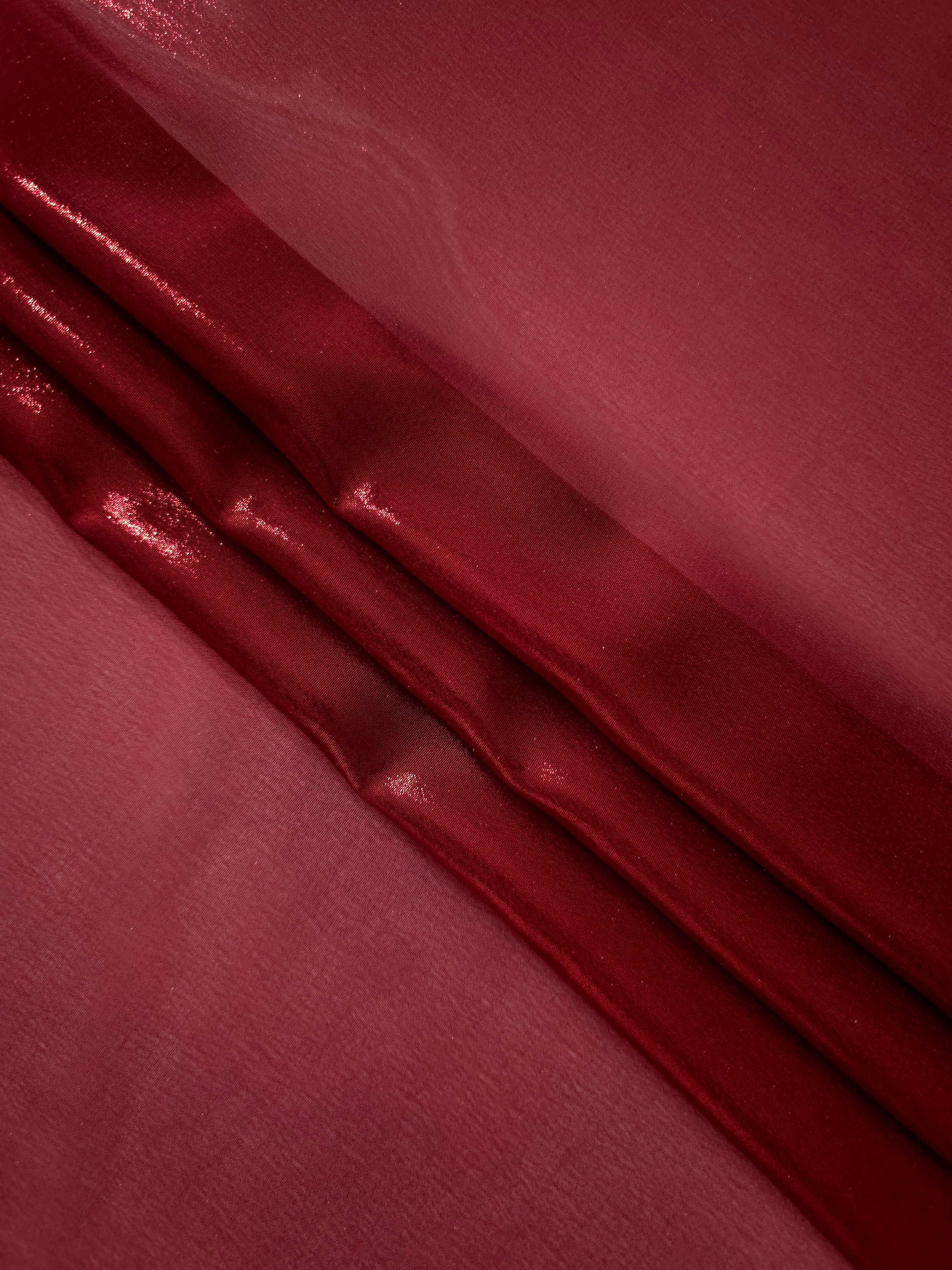 Deep burgundy flowing folds of liquid metallic shimmer chiffon fabric, showing lightweight reflective fabric texture and drape