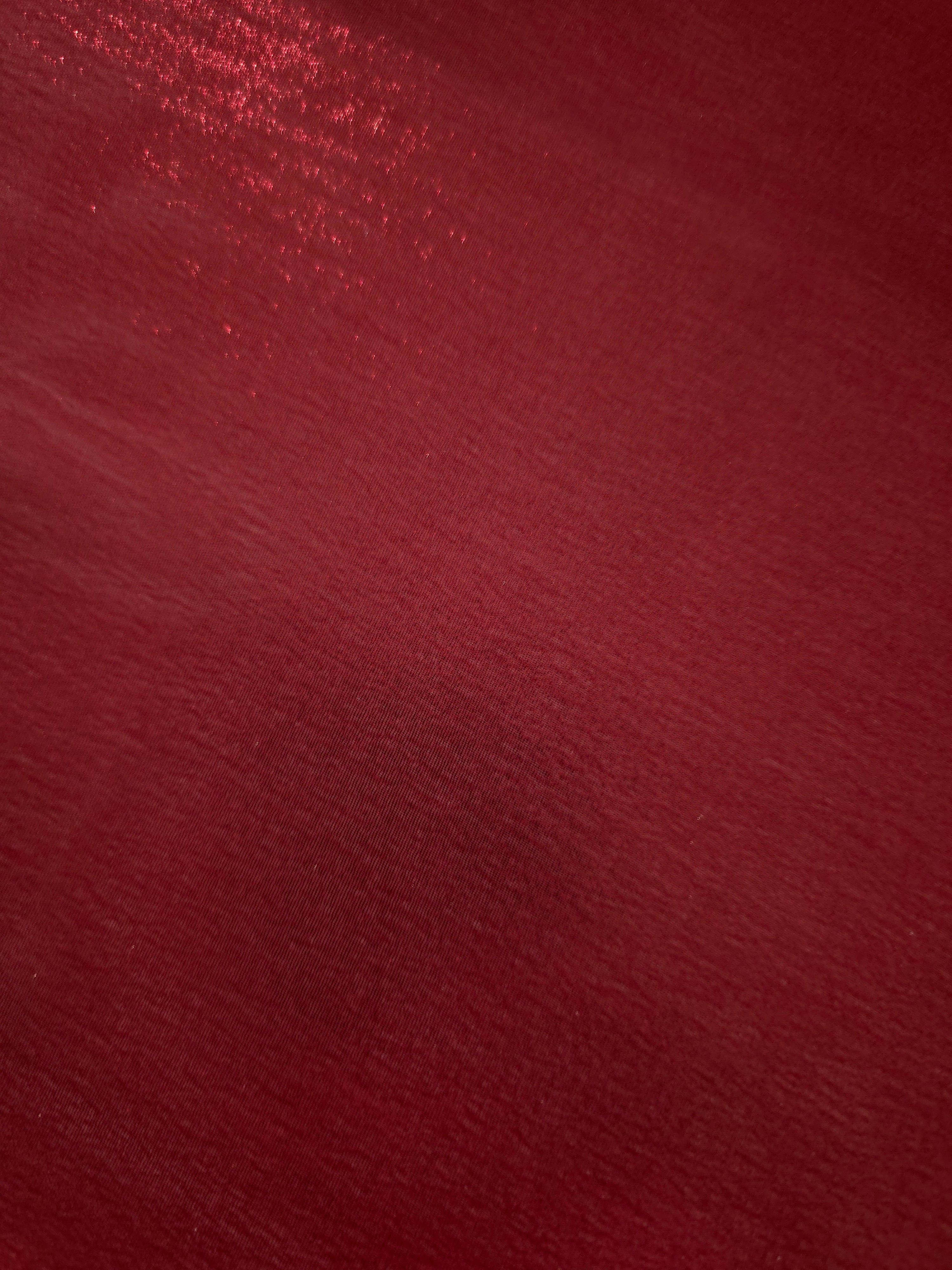 Deep burgundy fold detail of liquid metallic shimmer chiffon fabric, showing lightweight reflective fabric texture and drape