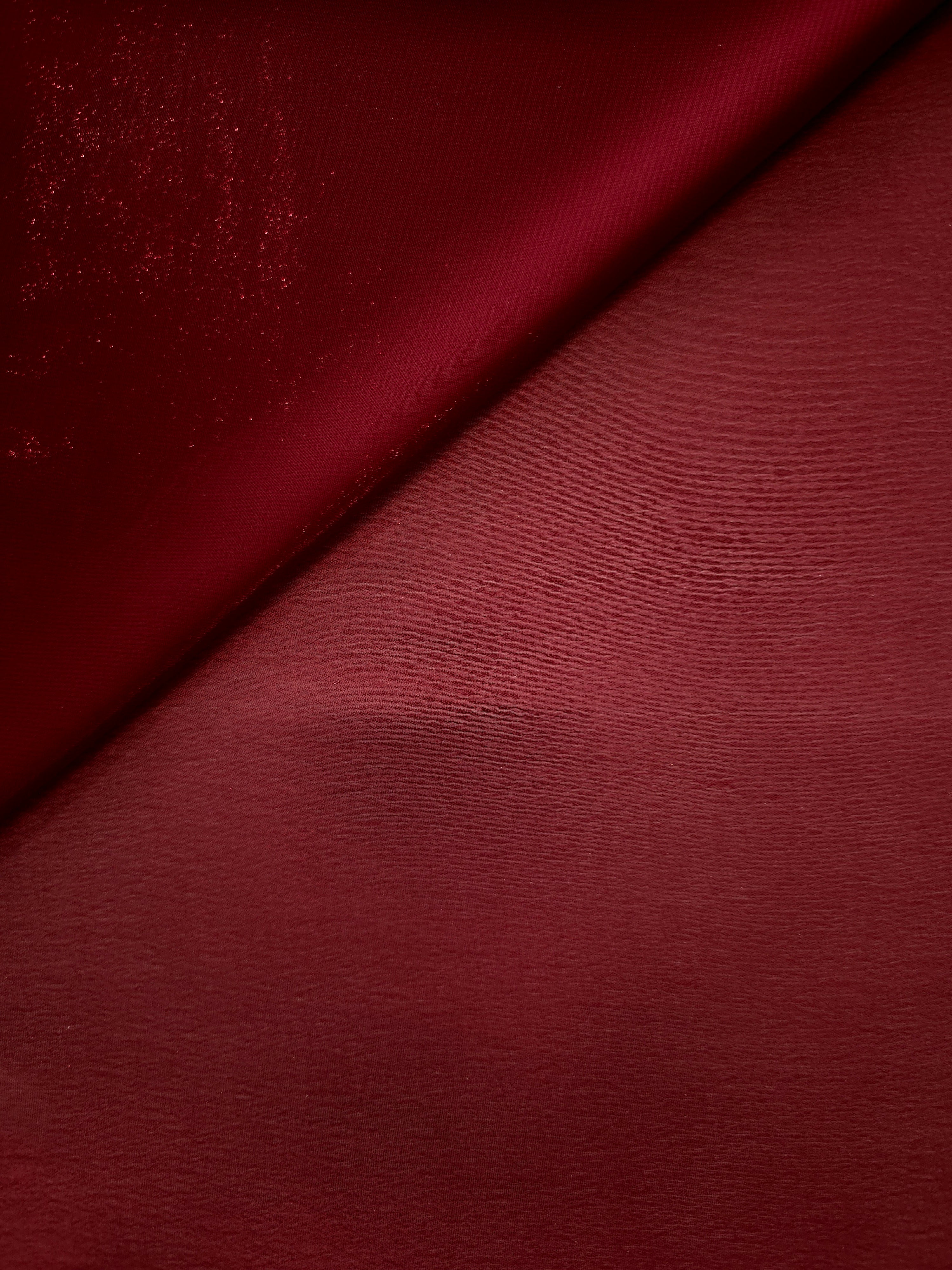 Deep burgundy soft draping view of liquid metallic shimmer chiffon fabric, highlighting fluid folds and reflective surface
