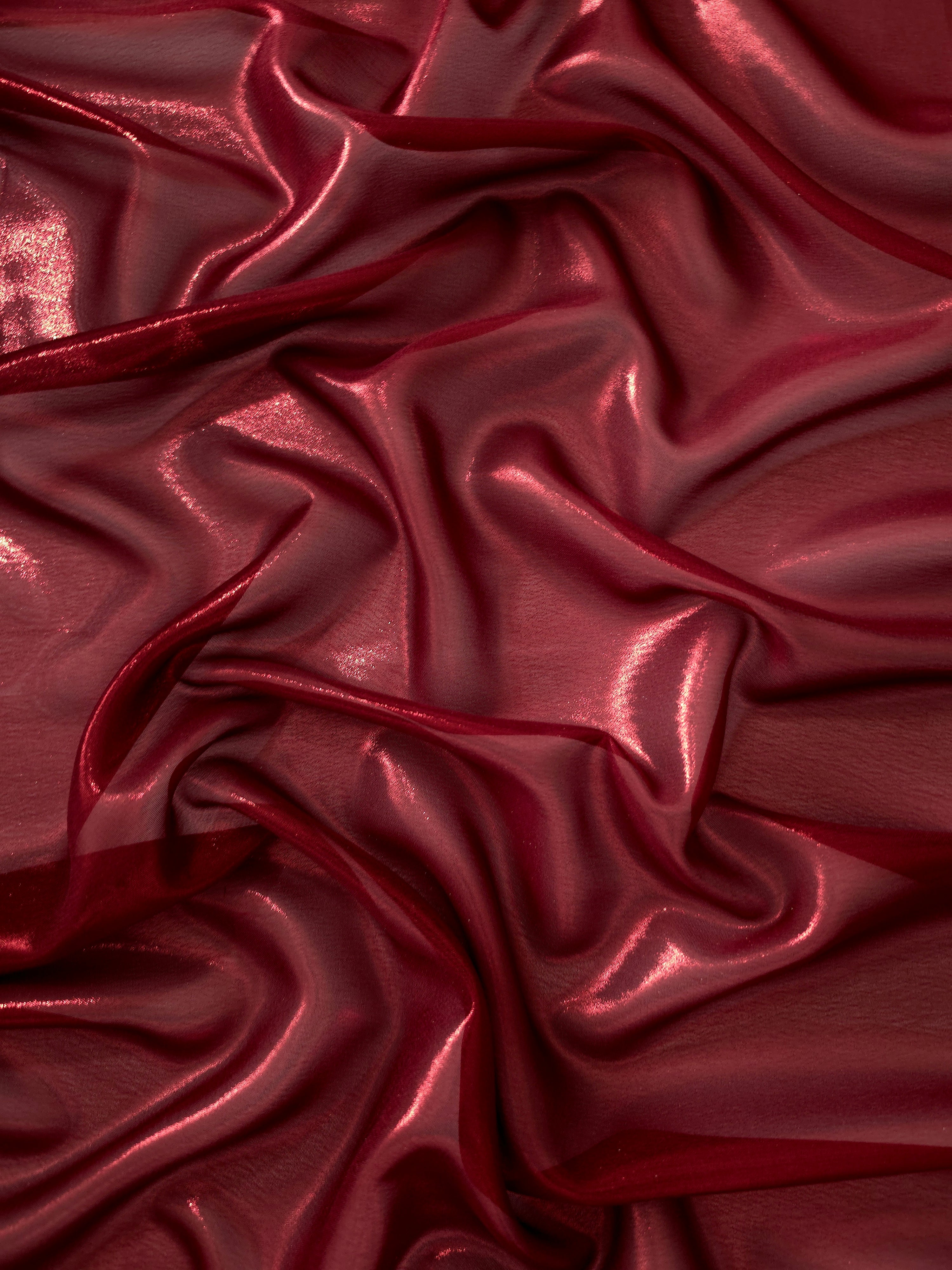 Deep burgundy surface detail of liquid metallic shimmer chiffon fabric, showing lightweight reflective fabric texture and drape