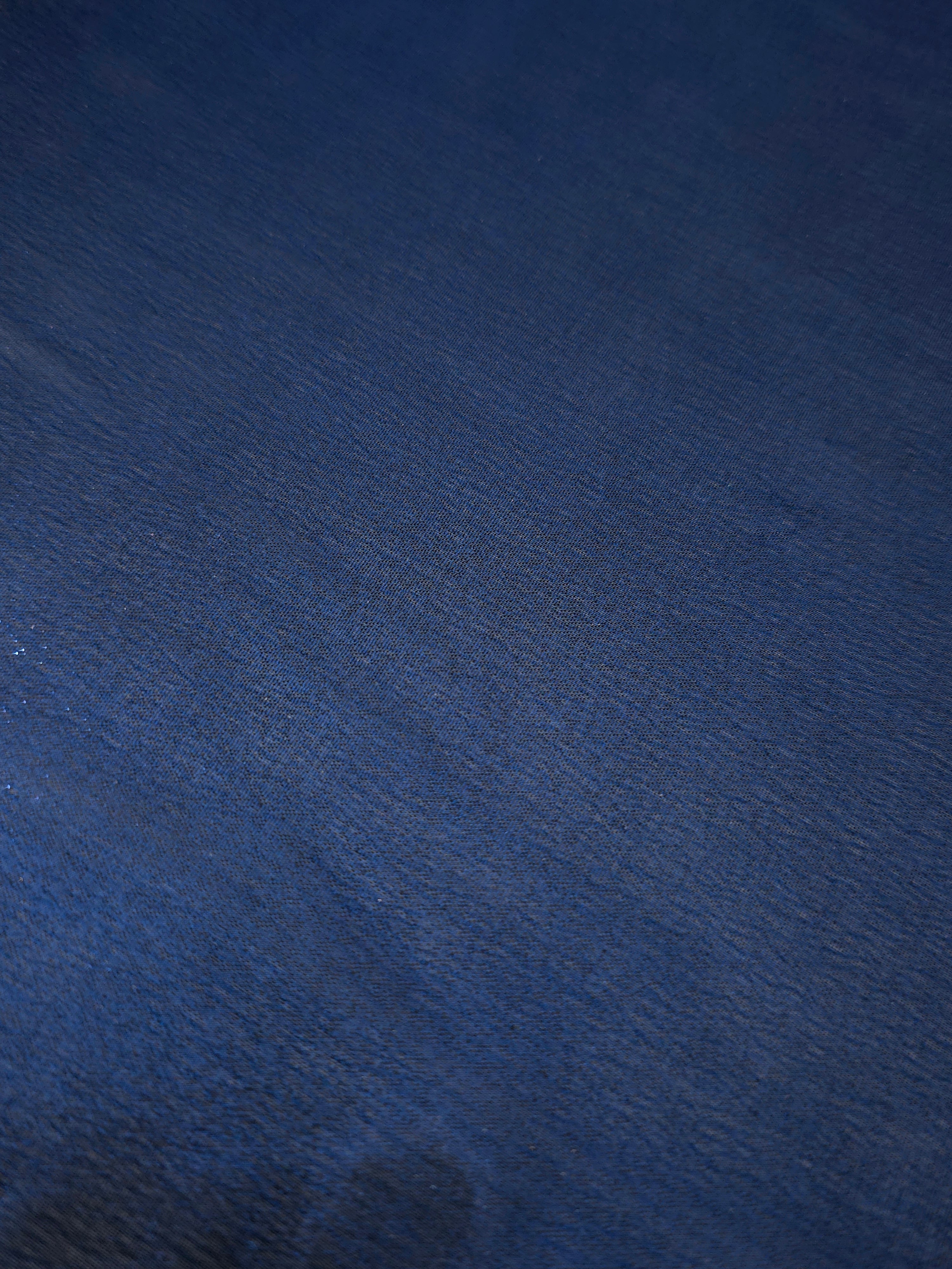 Deep indigo shimmer close-up of liquid metallic shimmer chiffon fabric, showing lightweight reflective fabric texture and drape