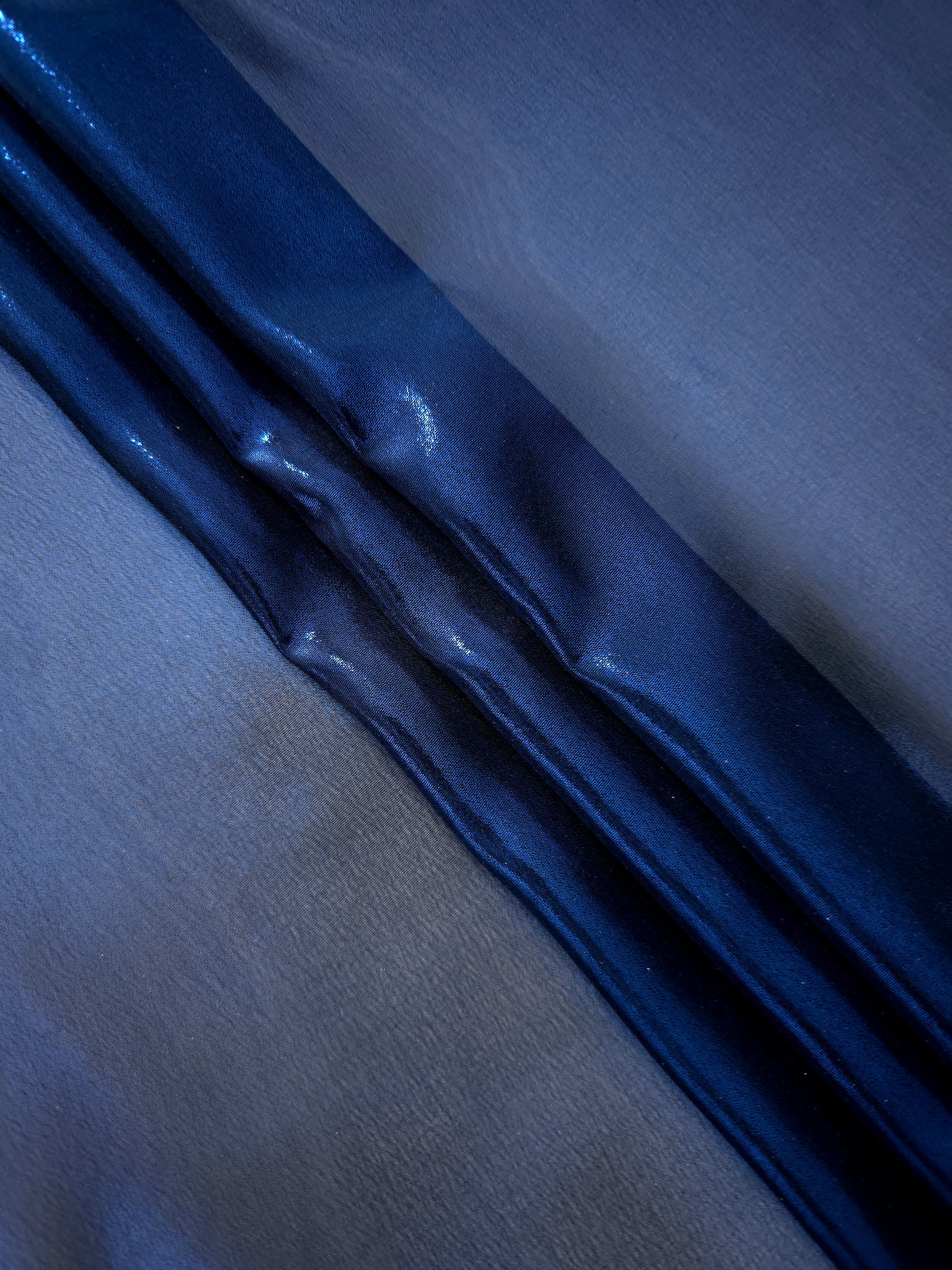 Deep indigo soft draping of liquid metallic shimmer chiffon fabric, showing lightweight reflective fabric texture and drape