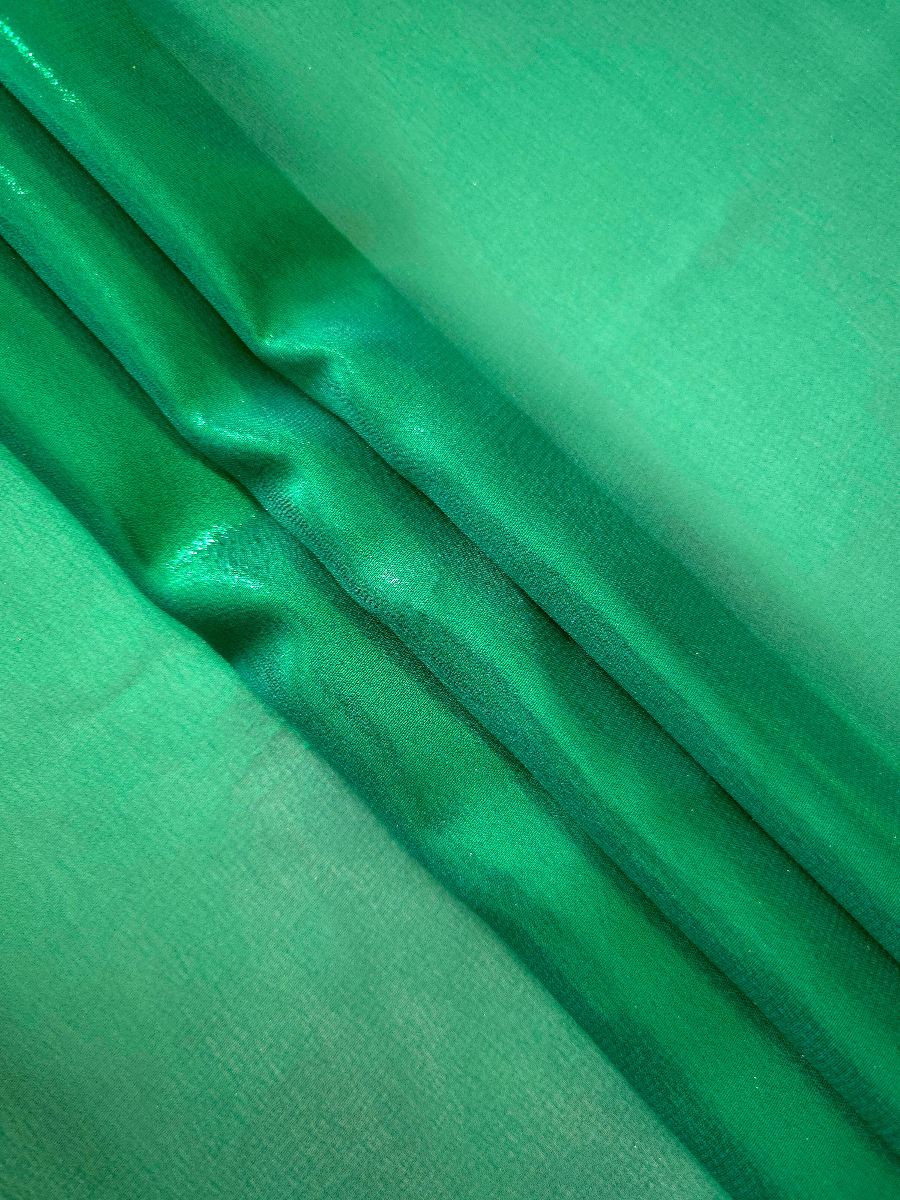 Emerald green flowing folds view of liquid metallic shimmer chiffon fabric, highlighting fluid folds and reflective surface