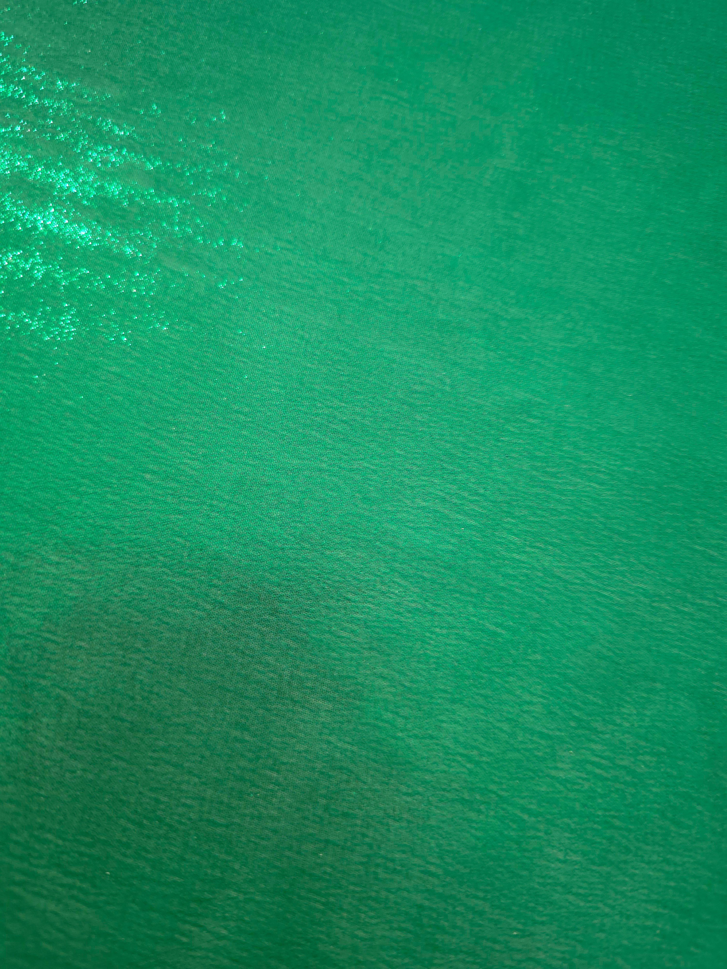 Emerald green fold detail view of liquid metallic shimmer chiffon fabric, highlighting fluid folds and reflective surface