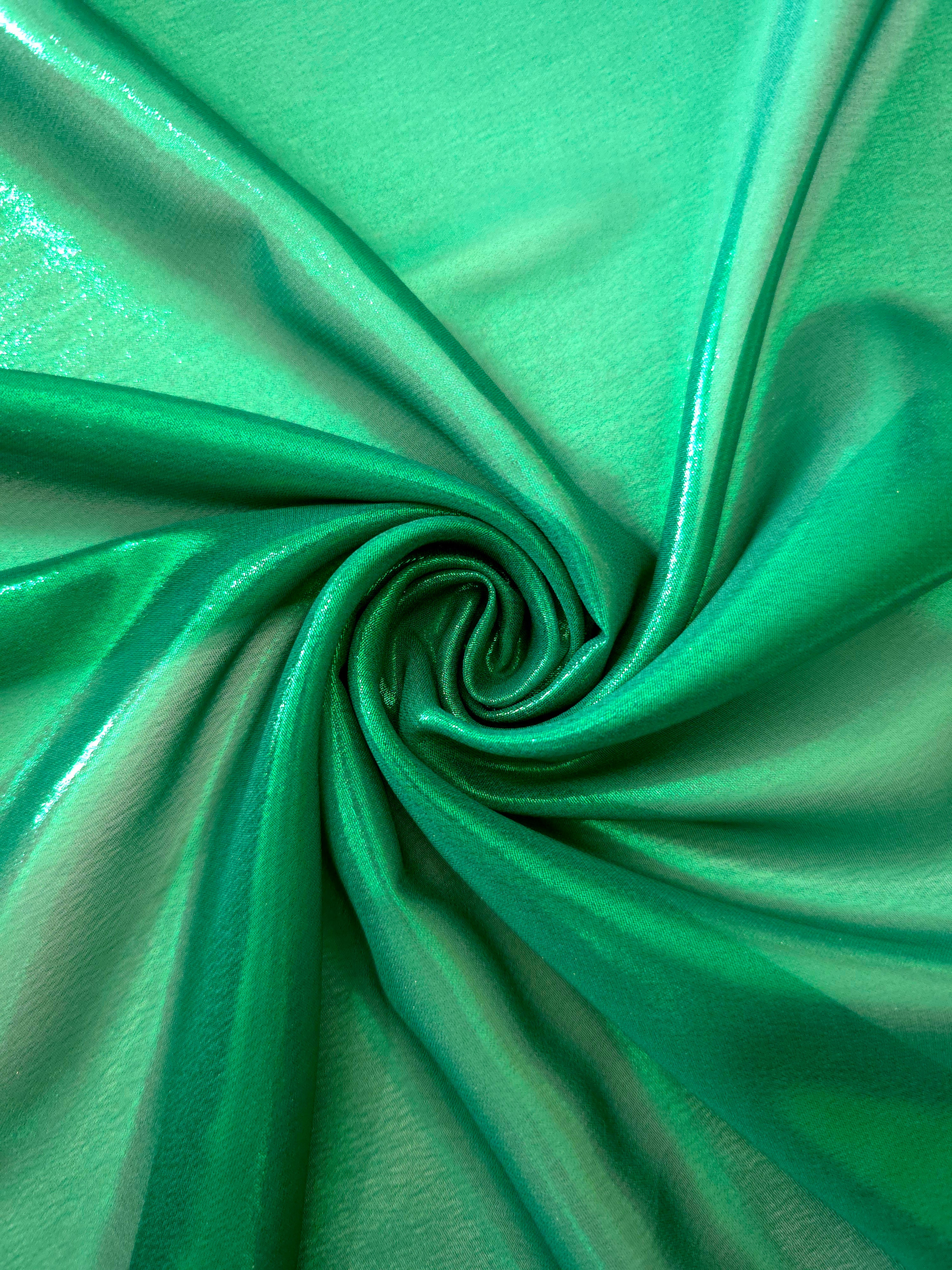 Emerald green shimmer close up view of liquid metallic shimmer chiffon fabric, highlighting fluid folds and reflective surface