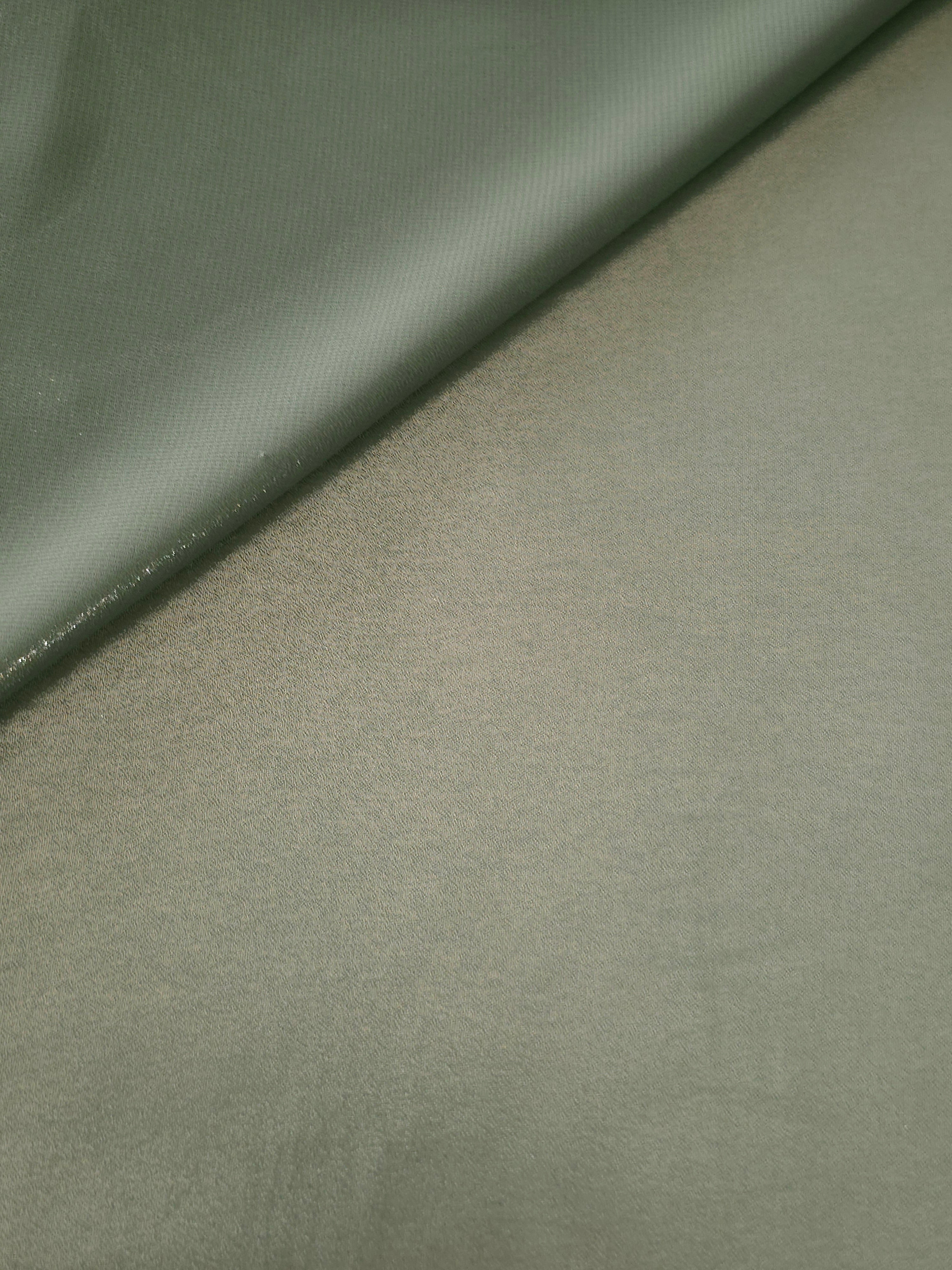Forest green fabric overview view of liquid metallic shimmer chiffon fabric, highlighting fluid folds and reflective surface