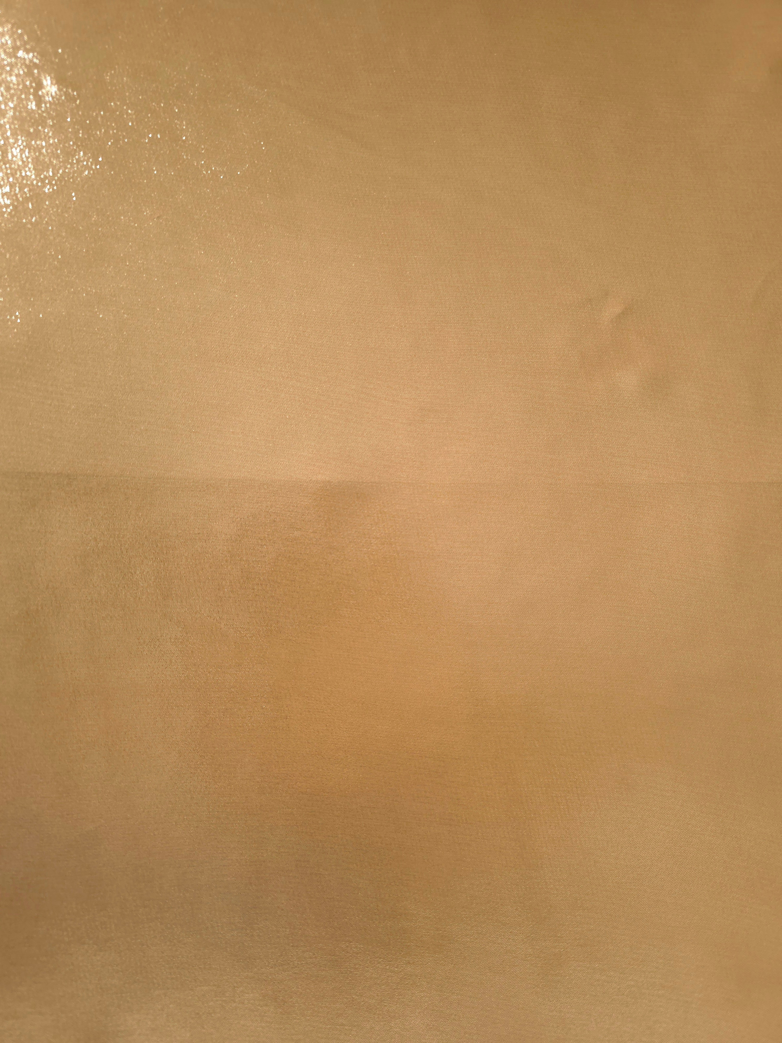 Golden sand fabric overview view of liquid metallic shimmer chiffon fabric, highlighting fluid folds and reflective surface