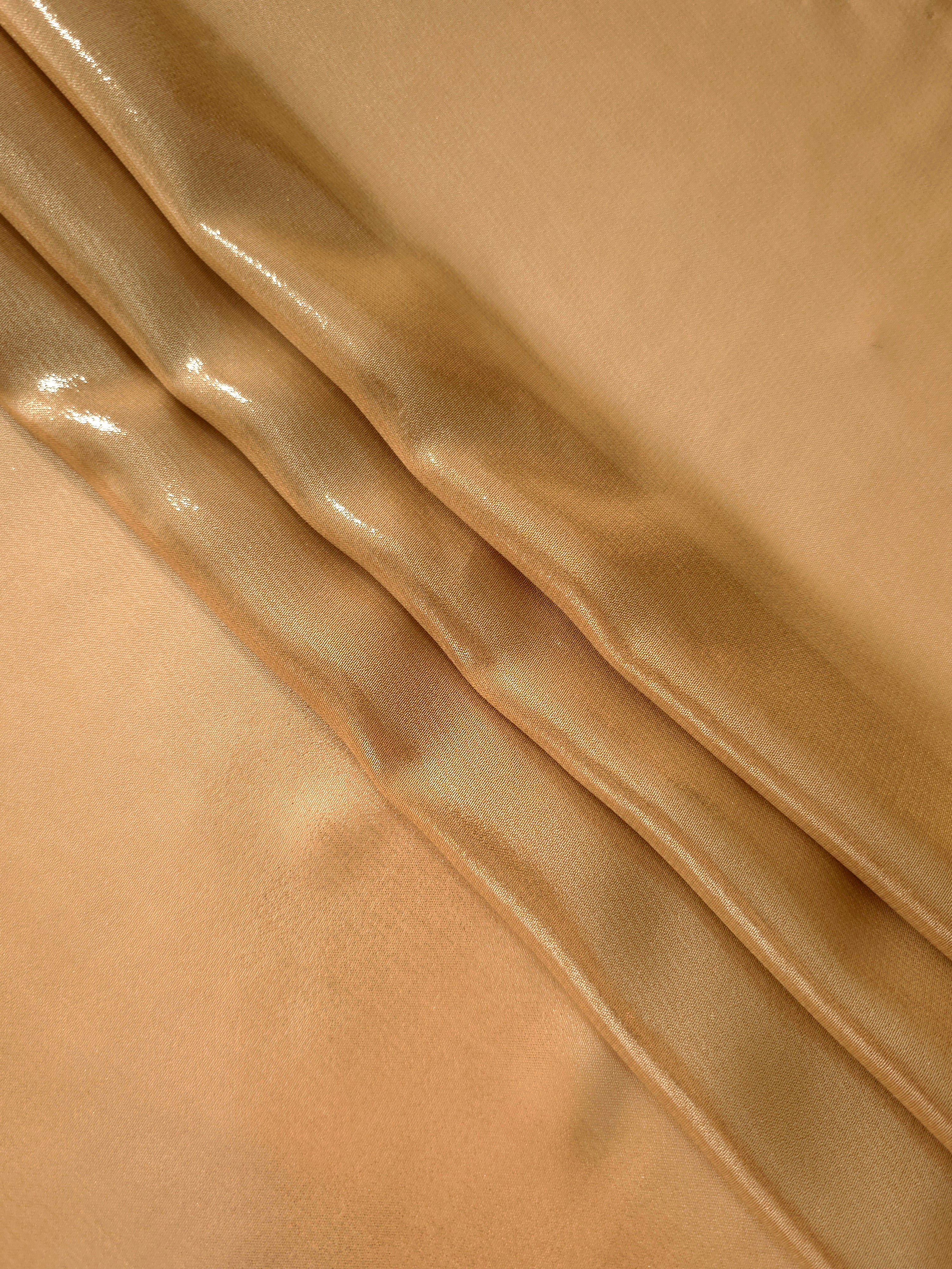 Golden sand flowing folds view of liquid metallic shimmer chiffon fabric, highlighting fluid folds and reflective surface