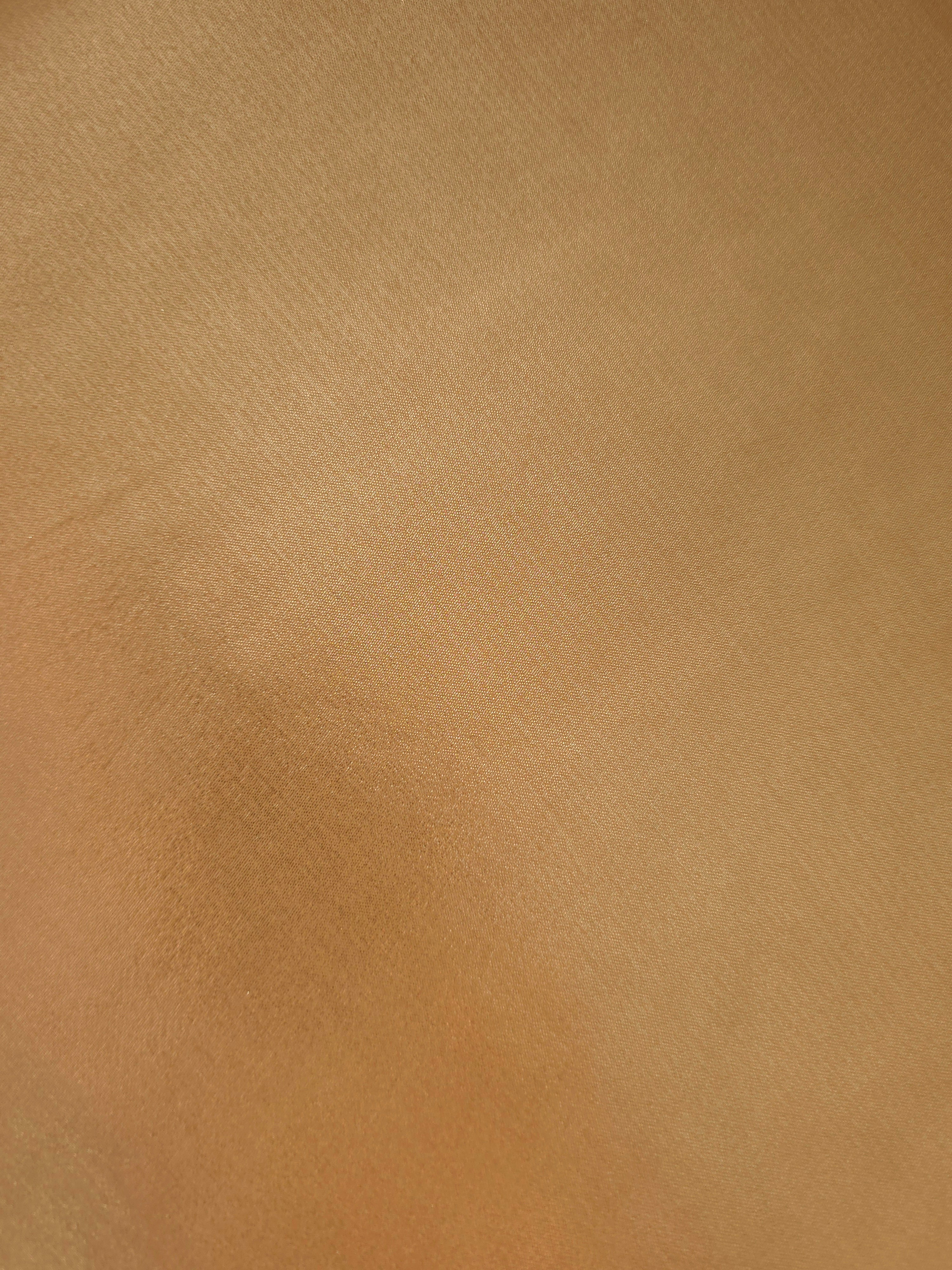 Golden sand fold detail view of liquid metallic shimmer chiffon fabric, highlighting fluid folds and reflective surface
