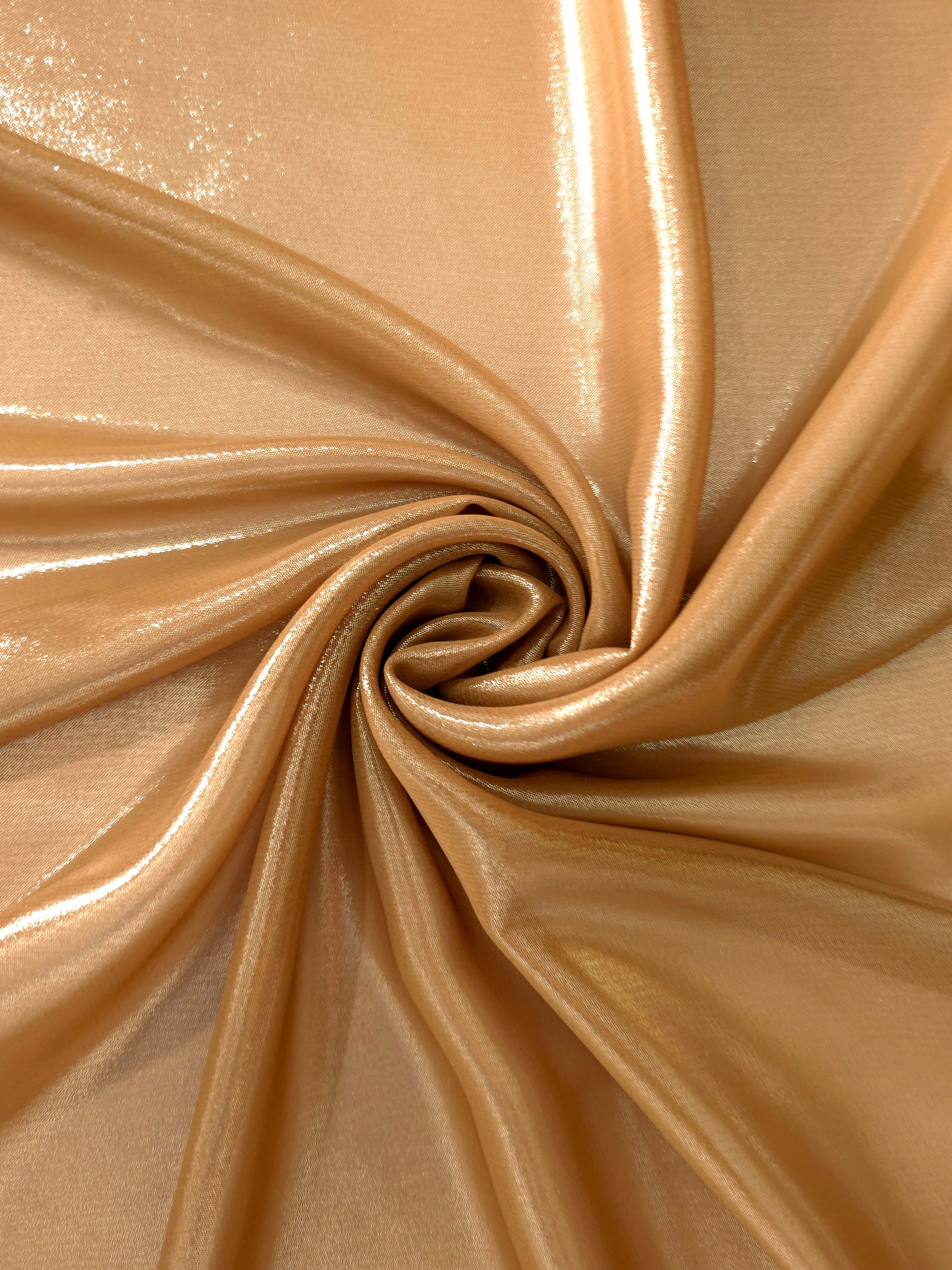Golden sand shimmer close up view of liquid metallic shimmer chiffon fabric, highlighting fluid folds and reflective surface