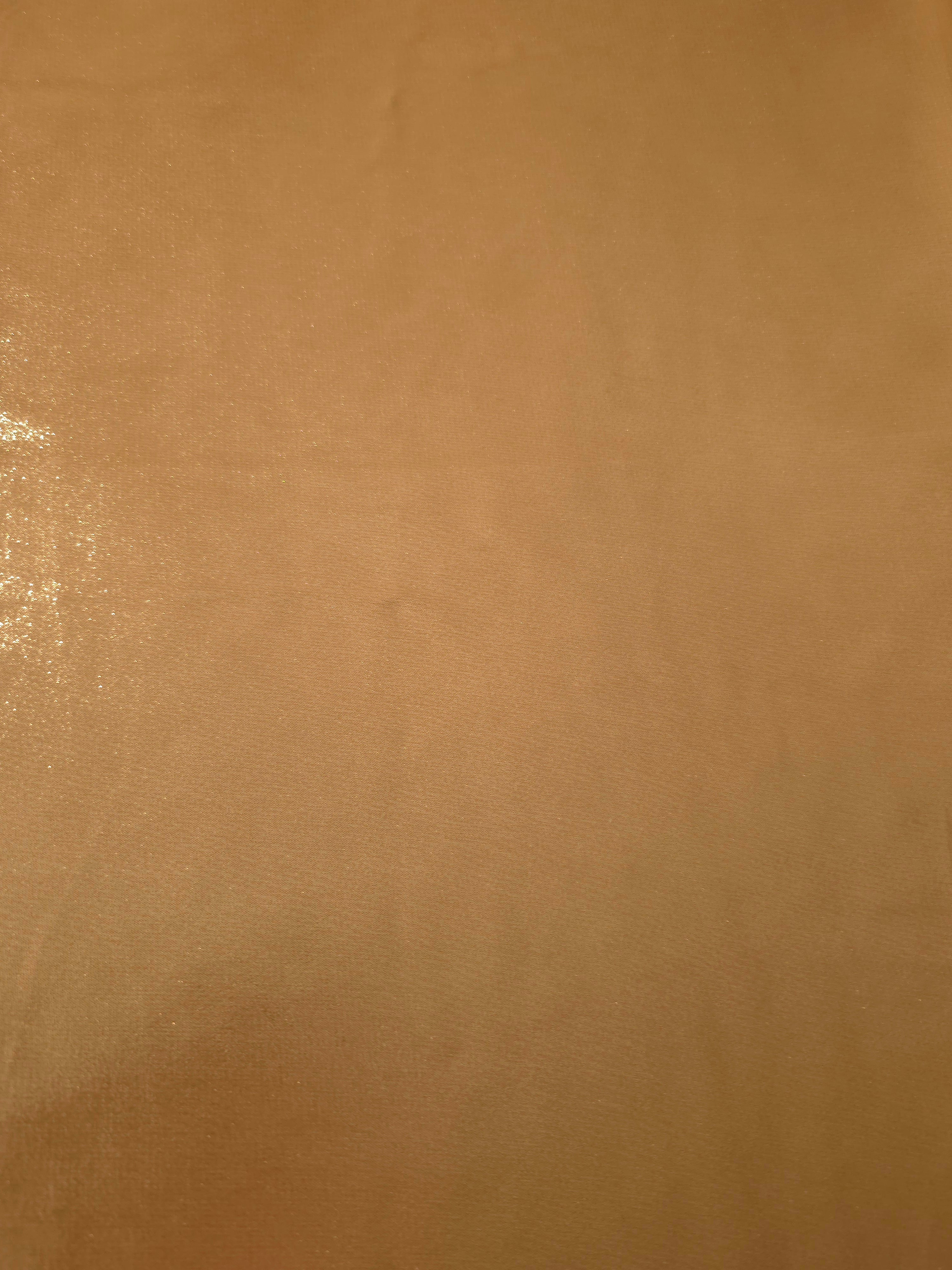 Golden tan fabric overview view of liquid metallic shimmer chiffon fabric, highlighting fluid folds and reflective surface