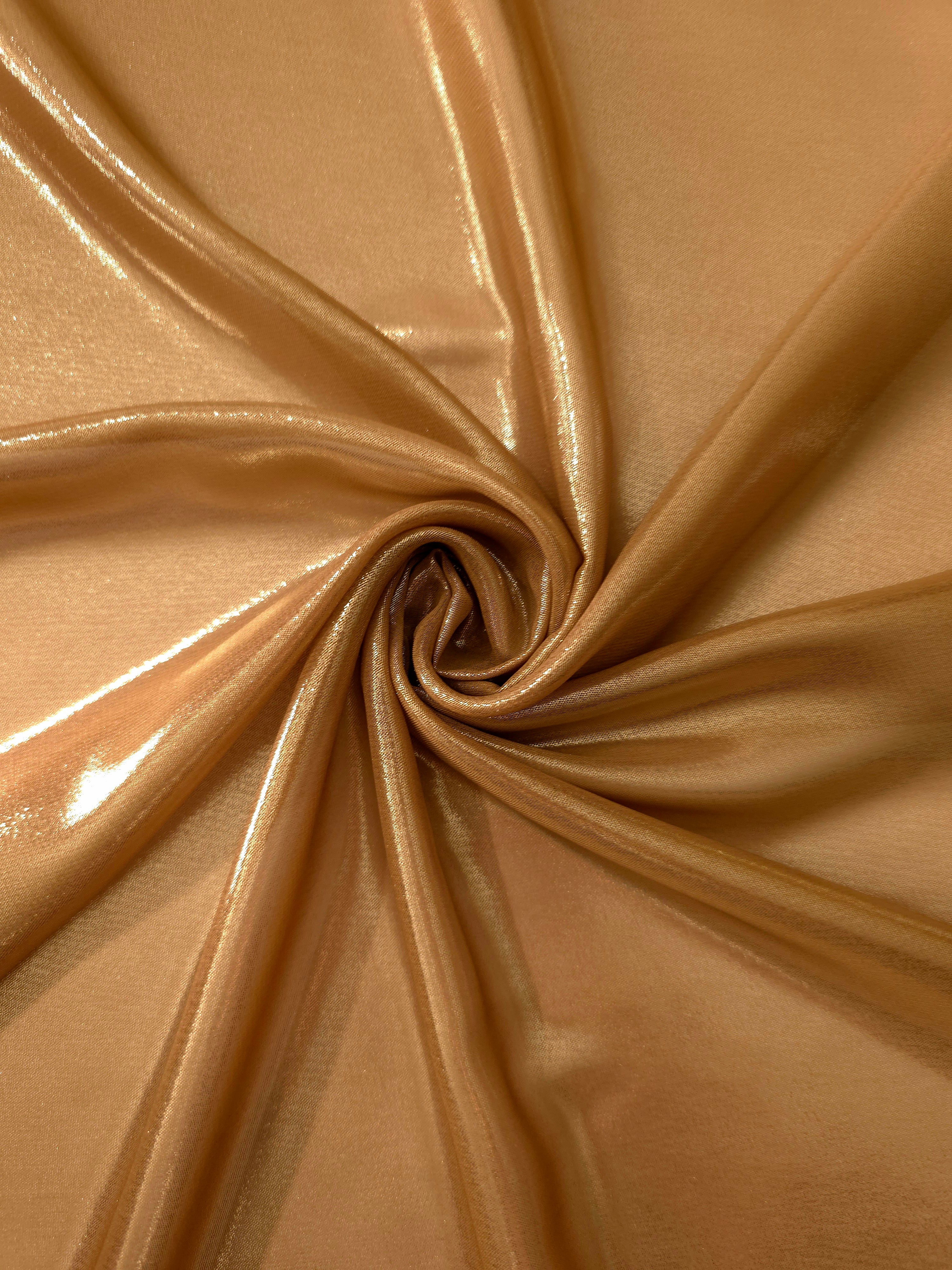 Golden tan shimmer close up view of liquid metallic shimmer chiffon fabric, highlighting fluid folds and reflective surface