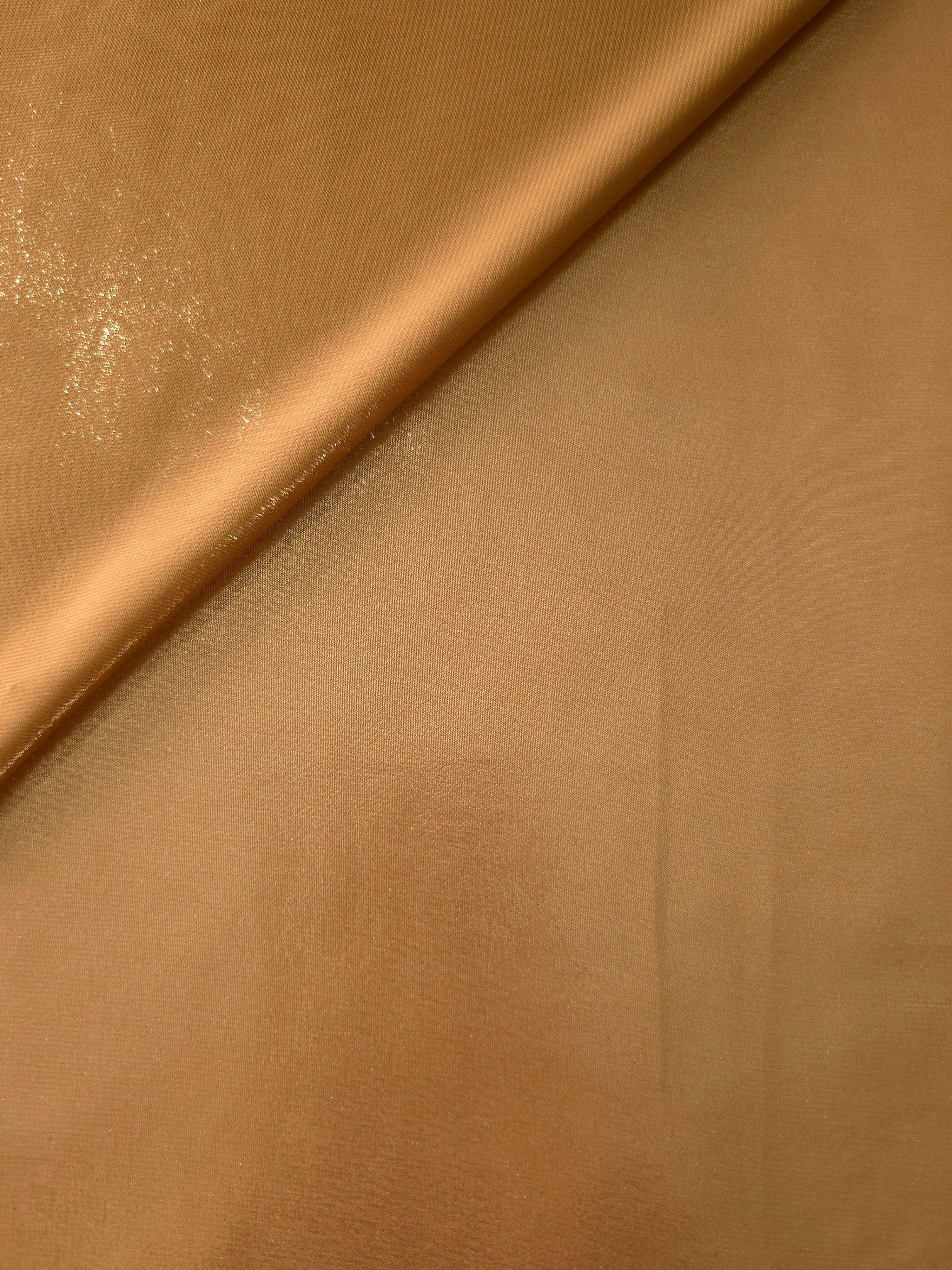 Golden tan soft draping view of liquid metallic shimmer chiffon fabric, highlighting fluid folds and reflective surface