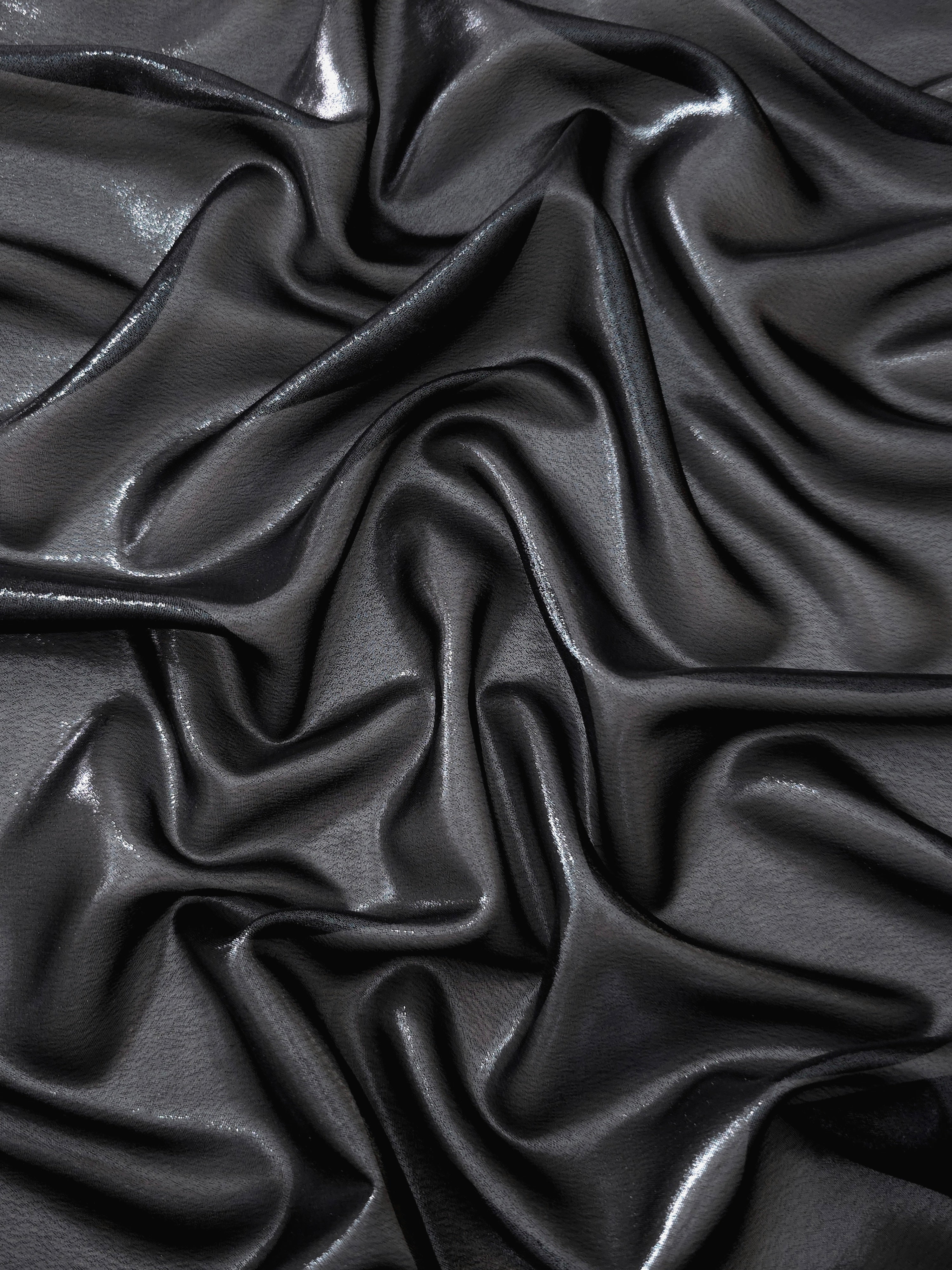 Midnight navy surface detail view of liquid metallic shimmer chiffon fabric, highlighting fluid folds and reflective surface