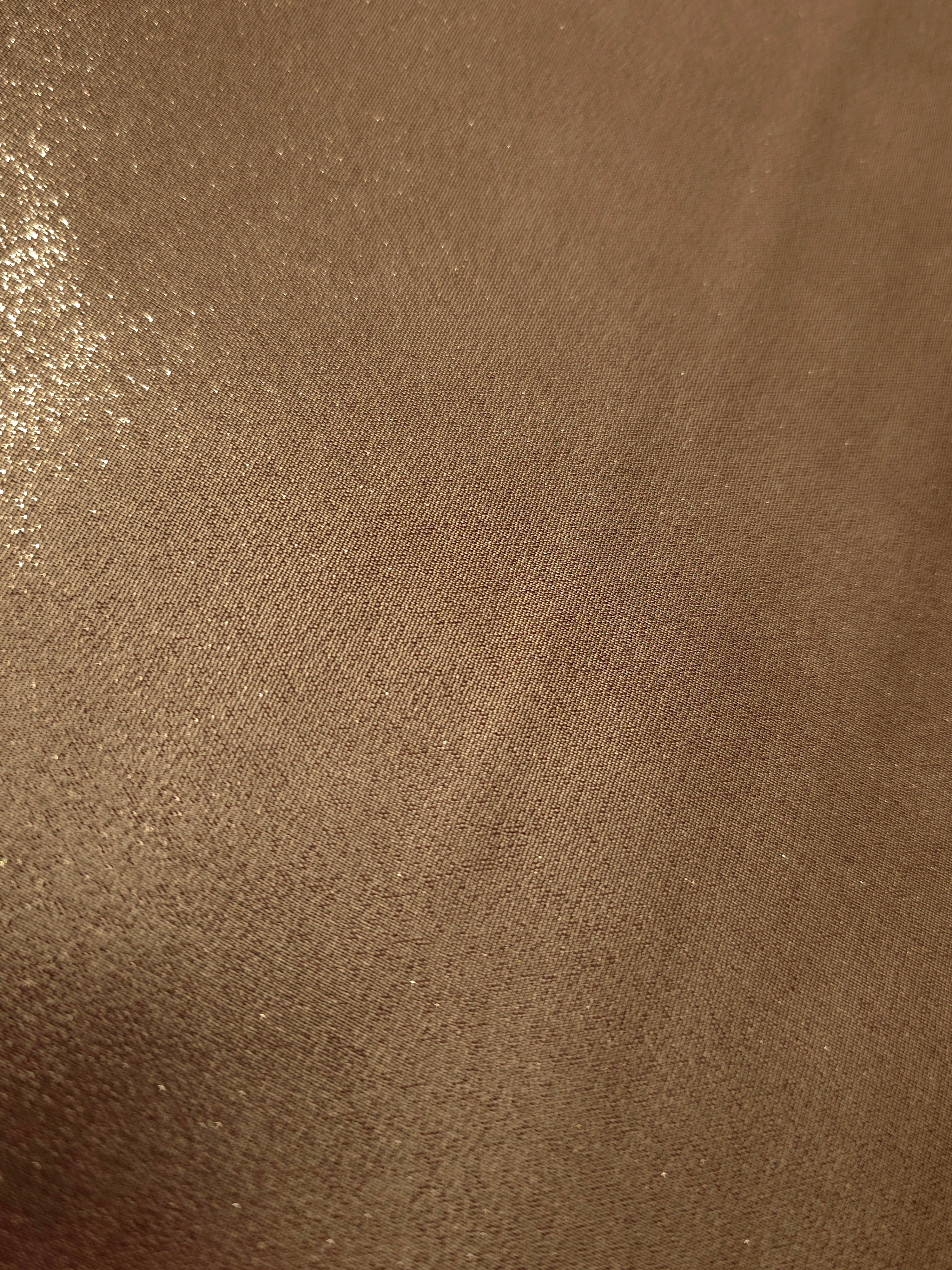 Mocha brown fold detail view of liquid metallic shimmer chiffon fabric, highlighting fluid folds and reflective surface