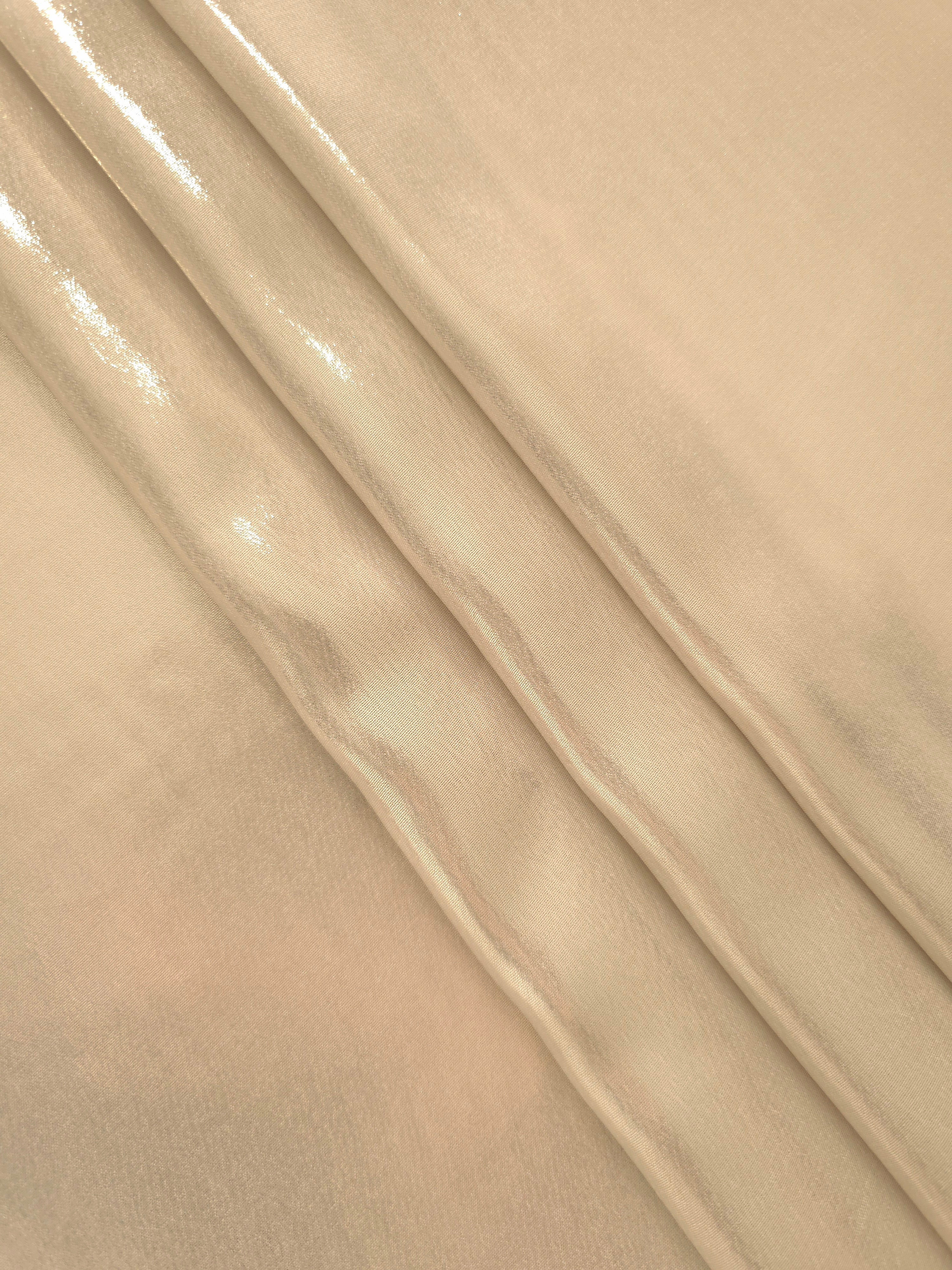 Nude champagne flowing folds of liquid metallic shimmer chiffon fabric, showing lightweight reflective fabric texture and drape