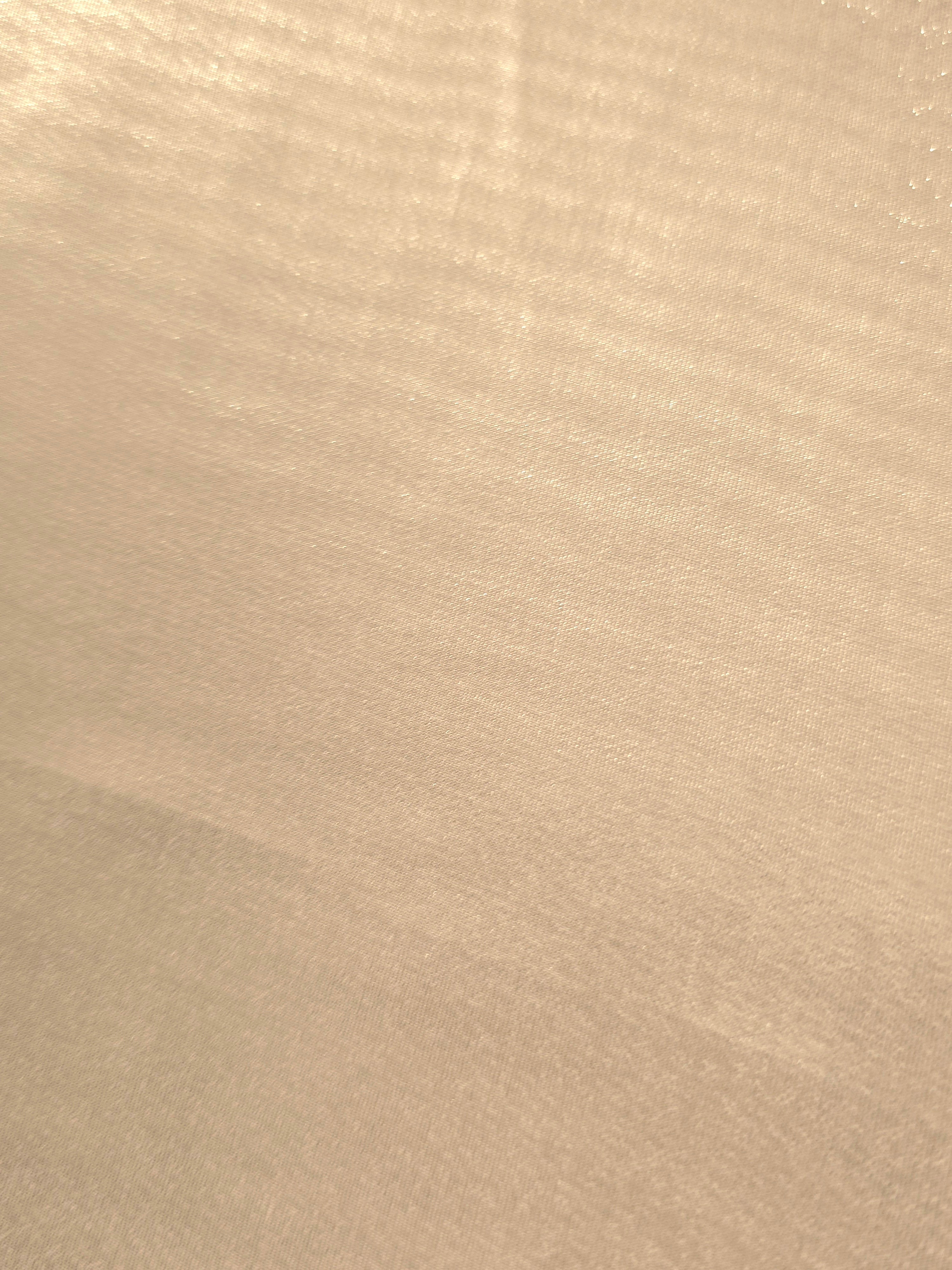 Nude champagne fold detail of liquid metallic shimmer chiffon fabric, showing lightweight reflective fabric texture and drape