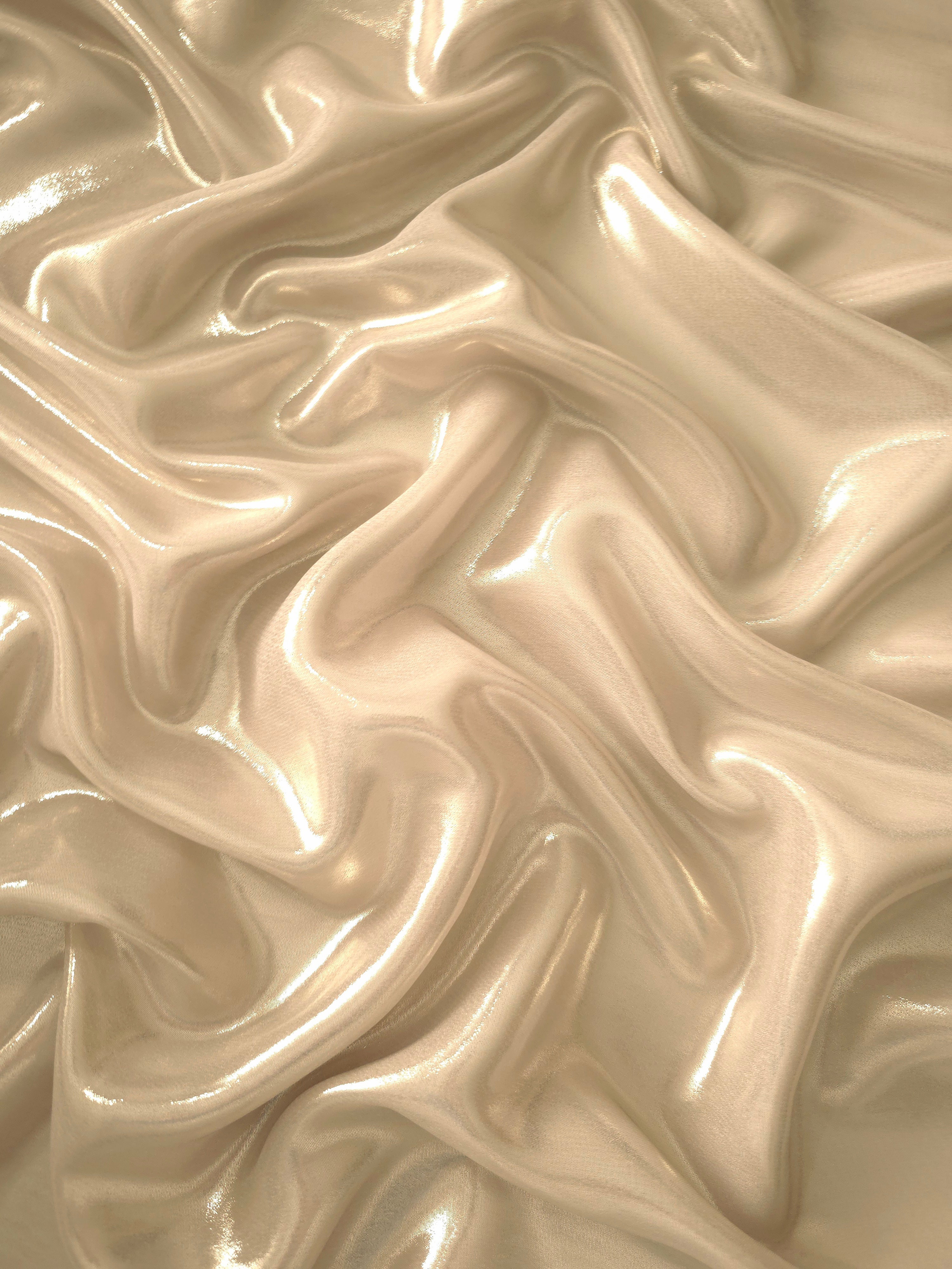 Nude champagne surface detail of liquid metallic shimmer chiffon fabric, showing lightweight reflective fabric texture and drape