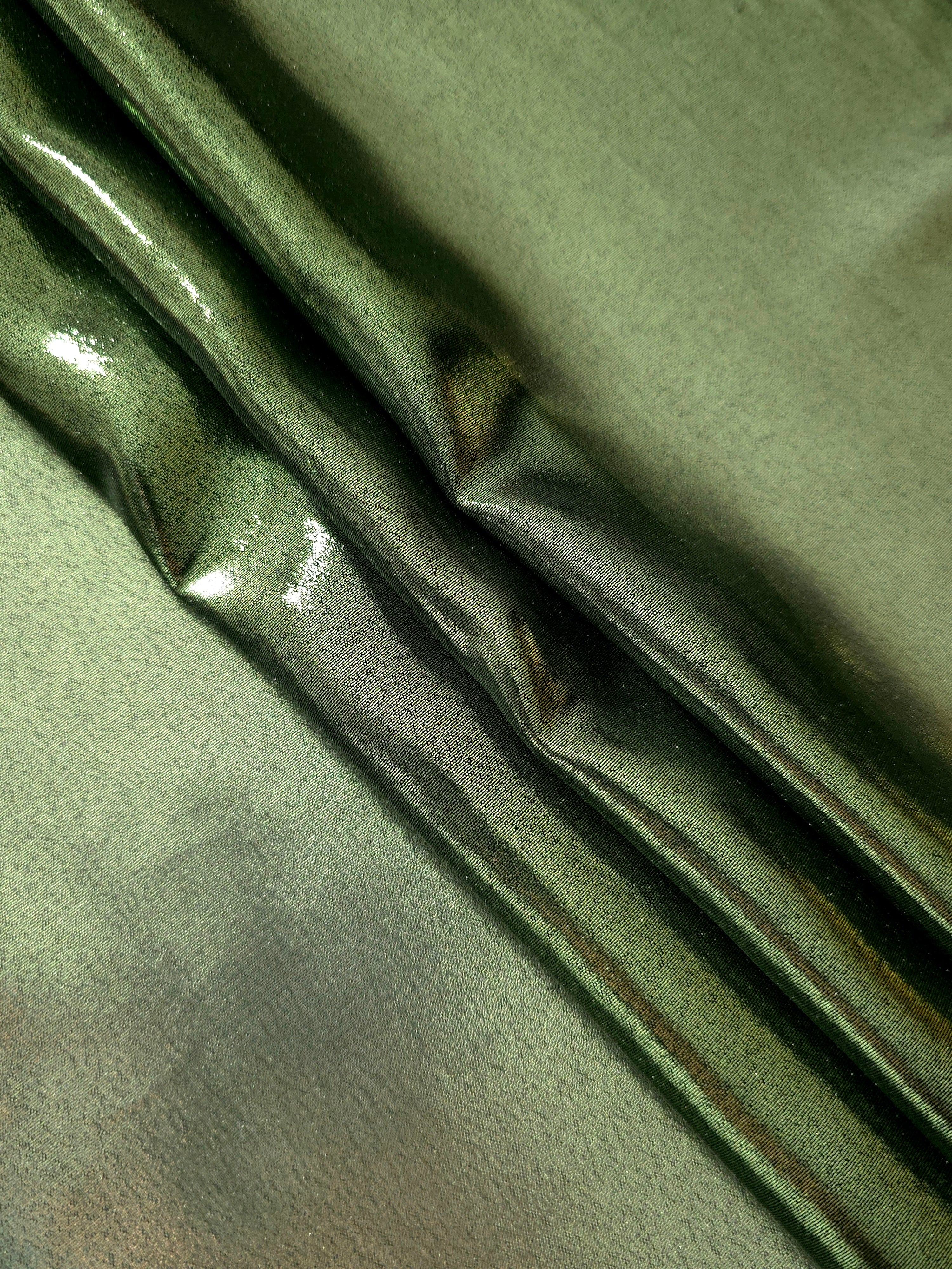 Olive green shimmer close up view of liquid metallic shimmer chiffon fabric, highlighting fluid folds and reflective surface