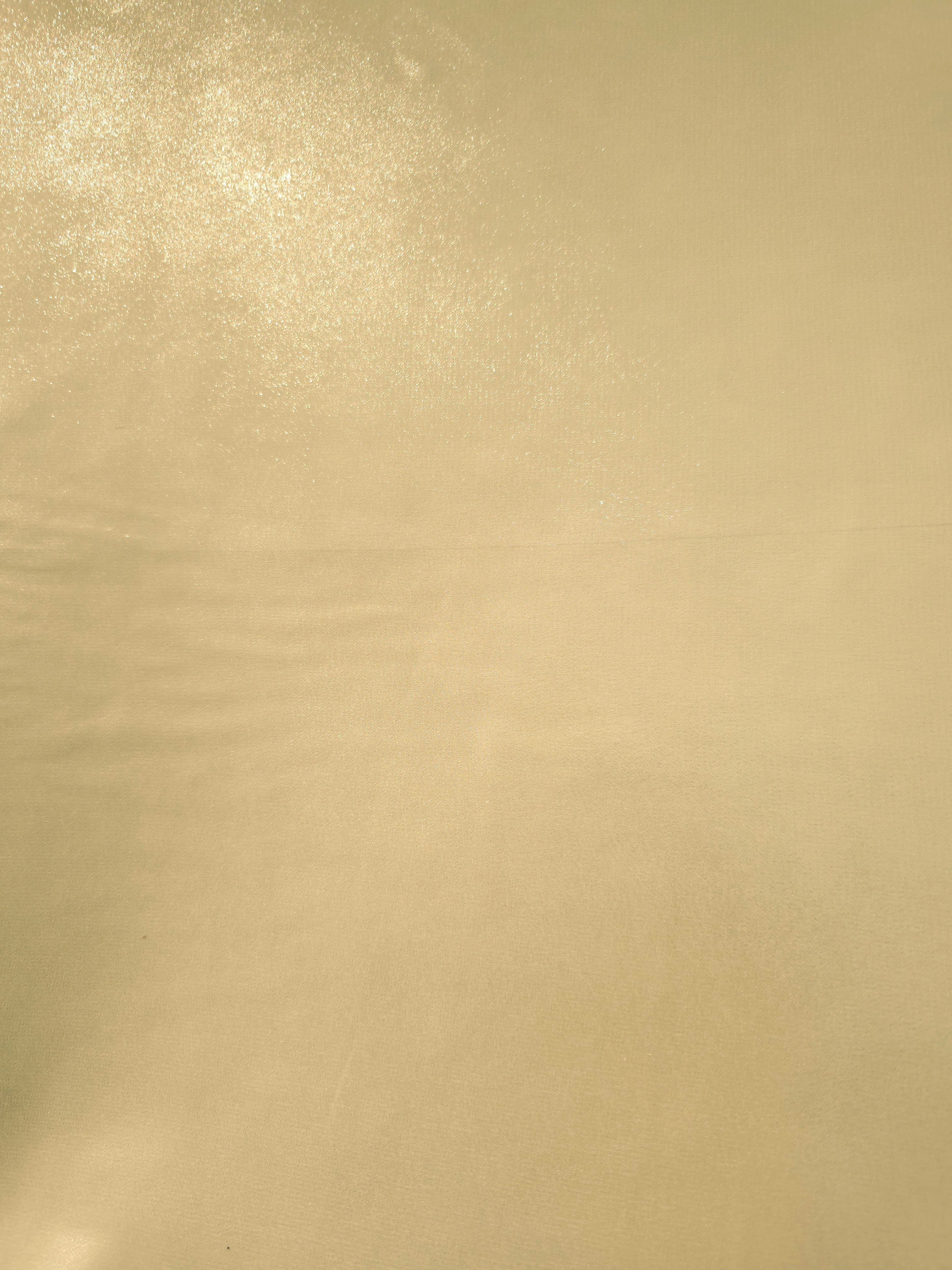 Pale gold fabric overview view of liquid metallic shimmer chiffon fabric, highlighting fluid folds and reflective surface
