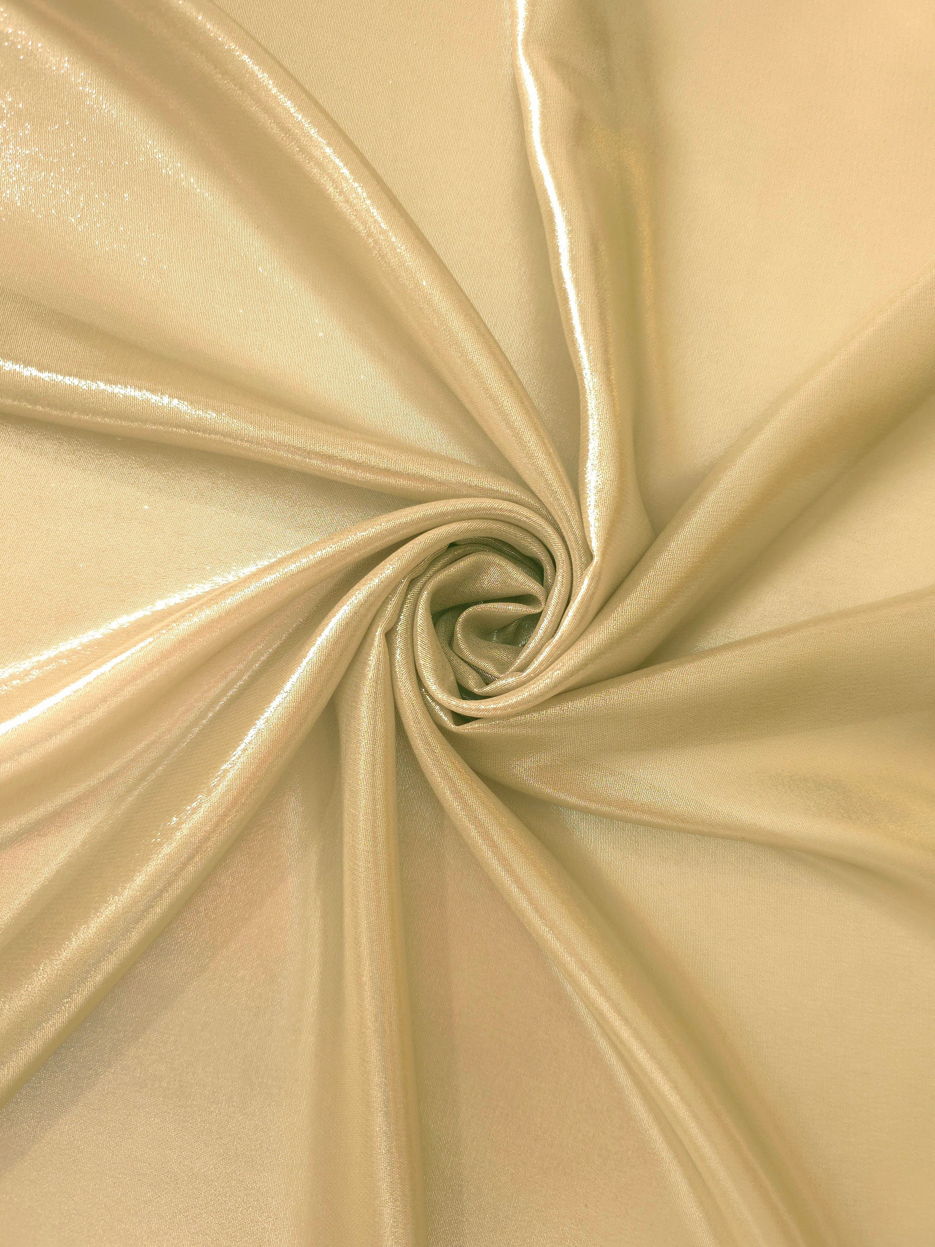 Pale gold shimmer close up view of liquid metallic shimmer chiffon fabric, highlighting fluid folds and reflective surface