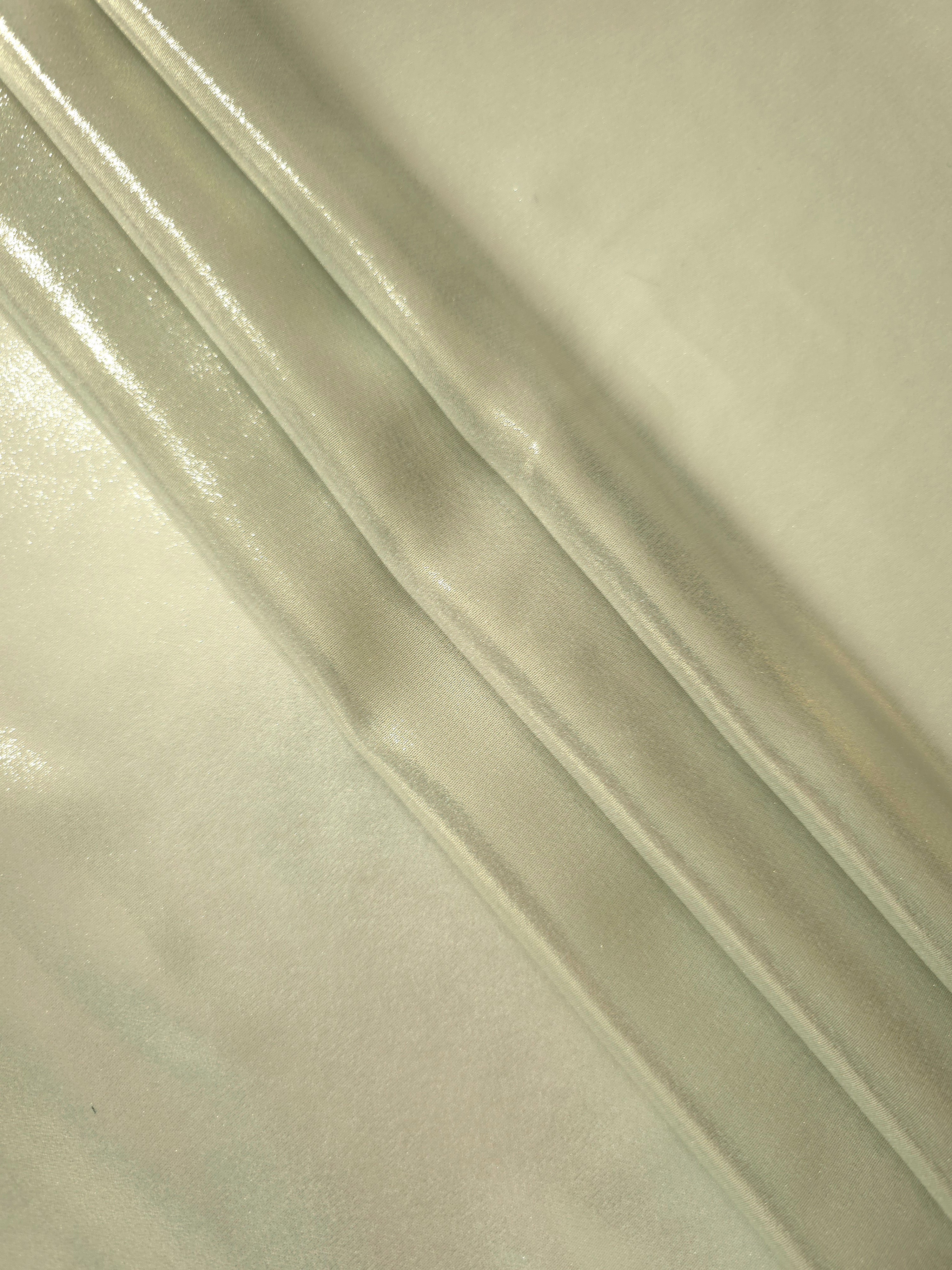 Pale pistachio flowing folds of liquid metallic shimmer chiffon fabric, showing lightweight reflective fabric texture and drape