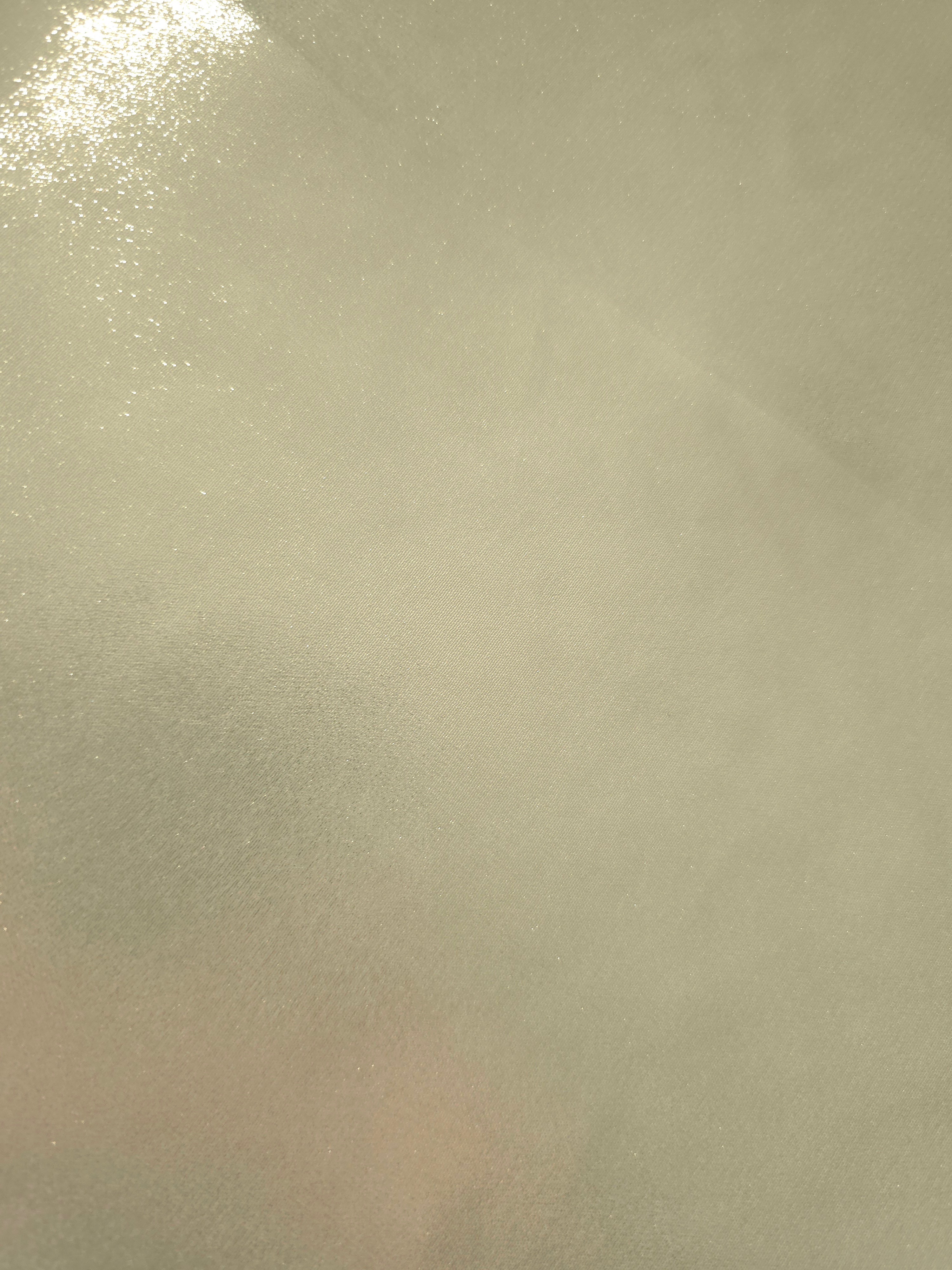 Pale pistachio fold detail of liquid metallic shimmer chiffon fabric, showing lightweight reflective fabric texture and drape