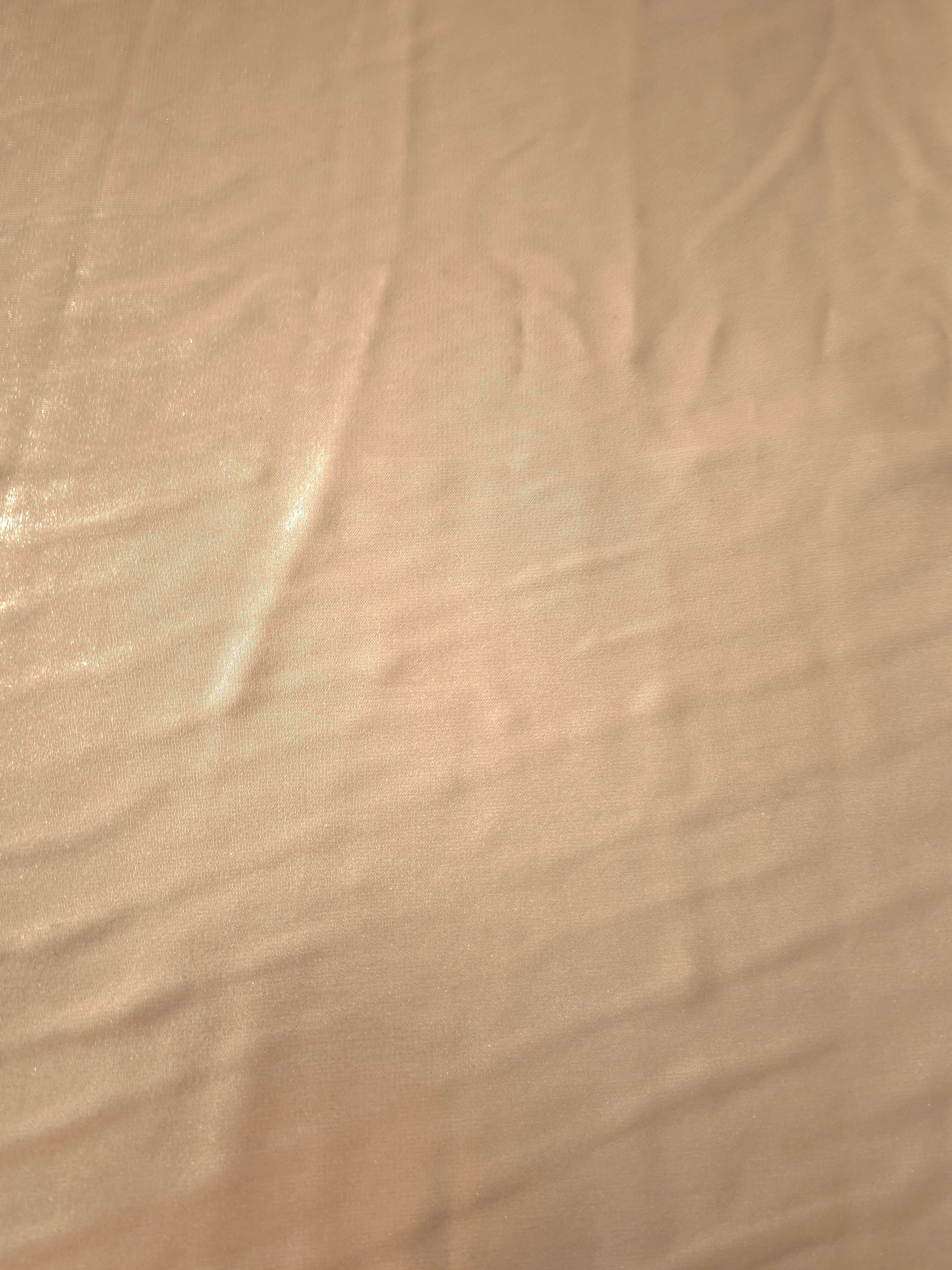 Peach champagne fabric overview view of liquid metallic shimmer chiffon fabric, highlighting fluid folds and reflective surface