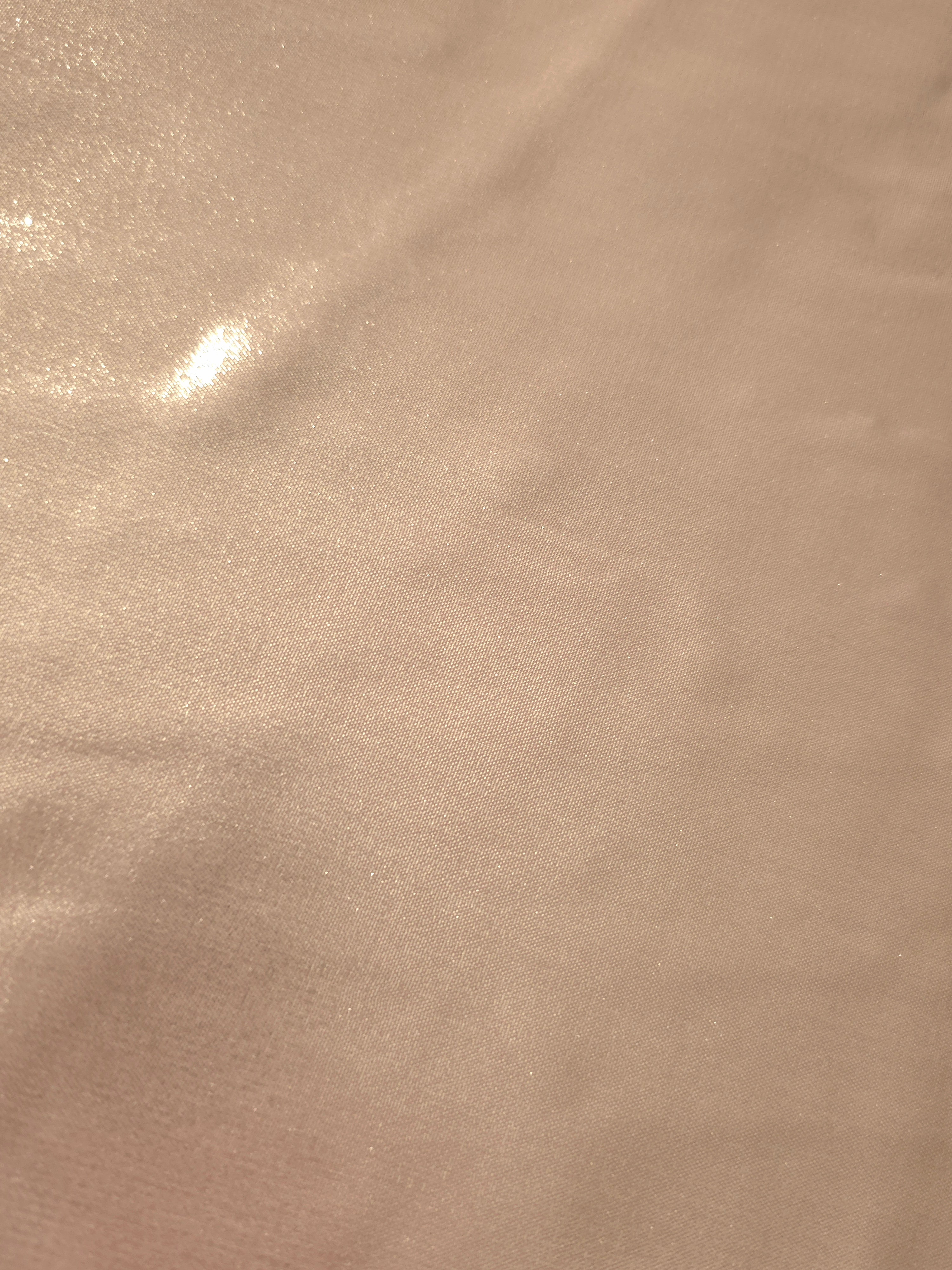 Peach champagne fold detail view of liquid metallic shimmer chiffon fabric, highlighting fluid folds and reflective surface