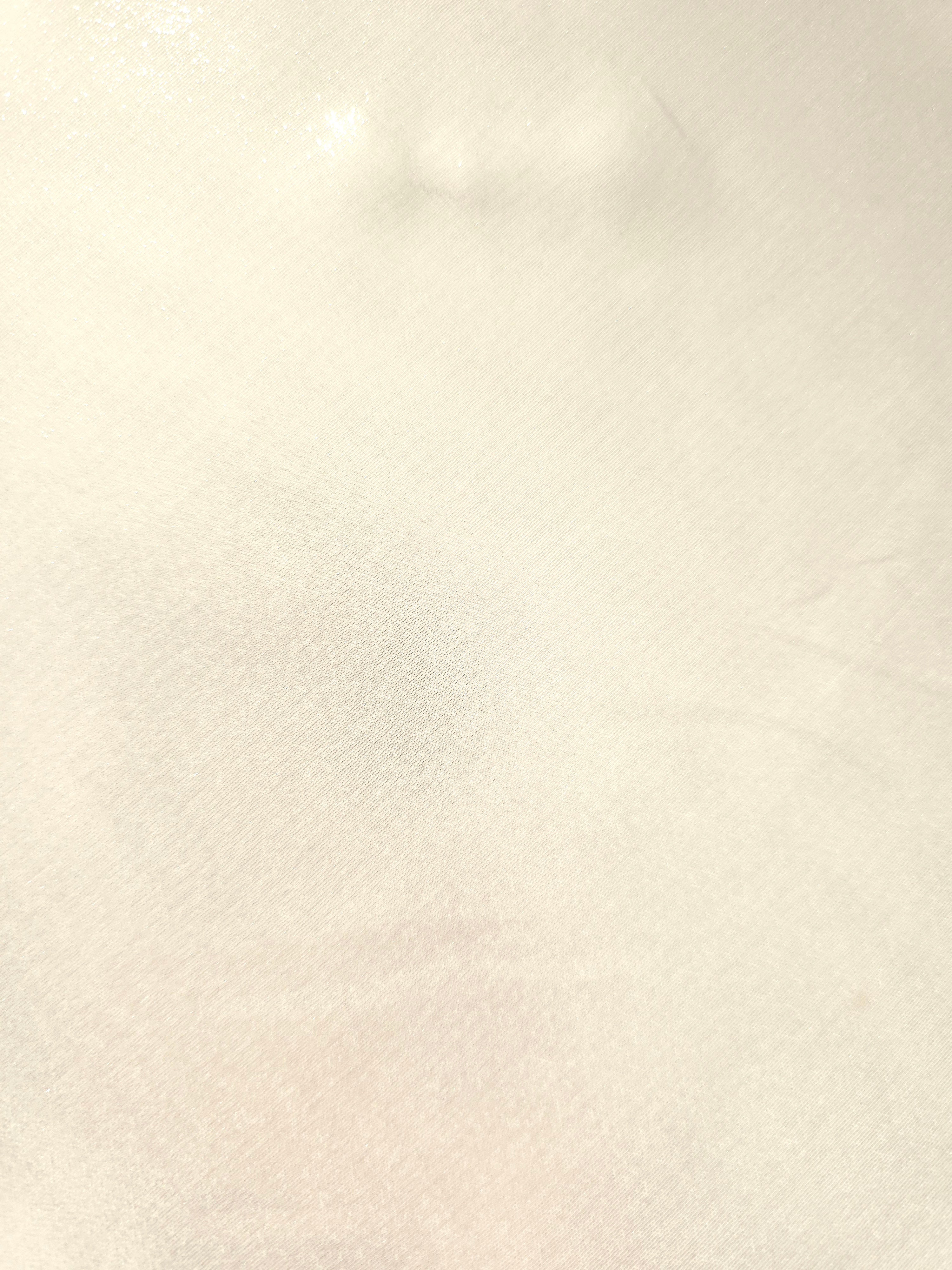 Pearl white fold detail of liquid metallic shimmer chiffon fabric, showing lightweight reflective fabric texture and drape