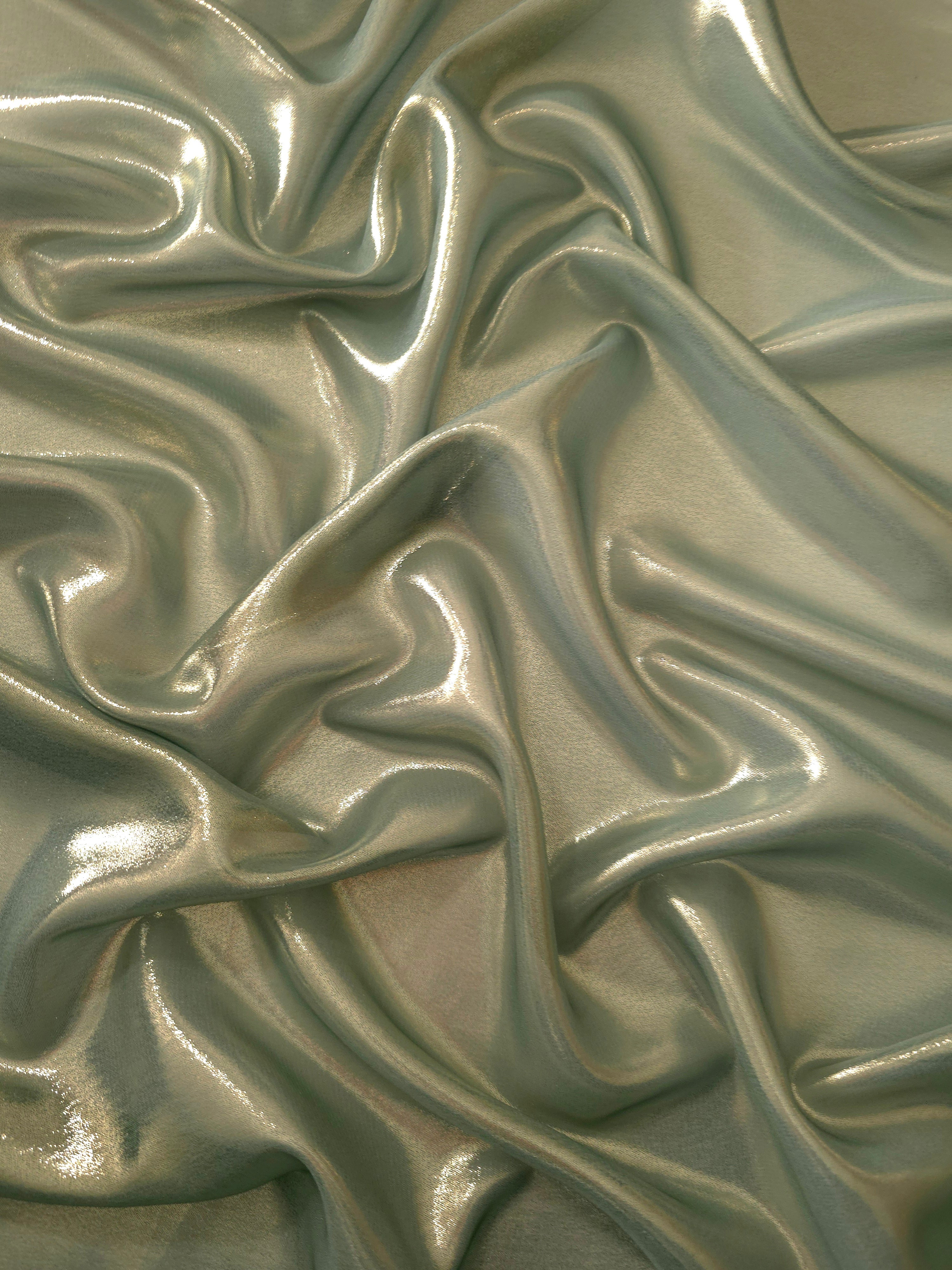 Sage green surface detail view of liquid metallic shimmer chiffon fabric, highlighting fluid folds and reflective surface