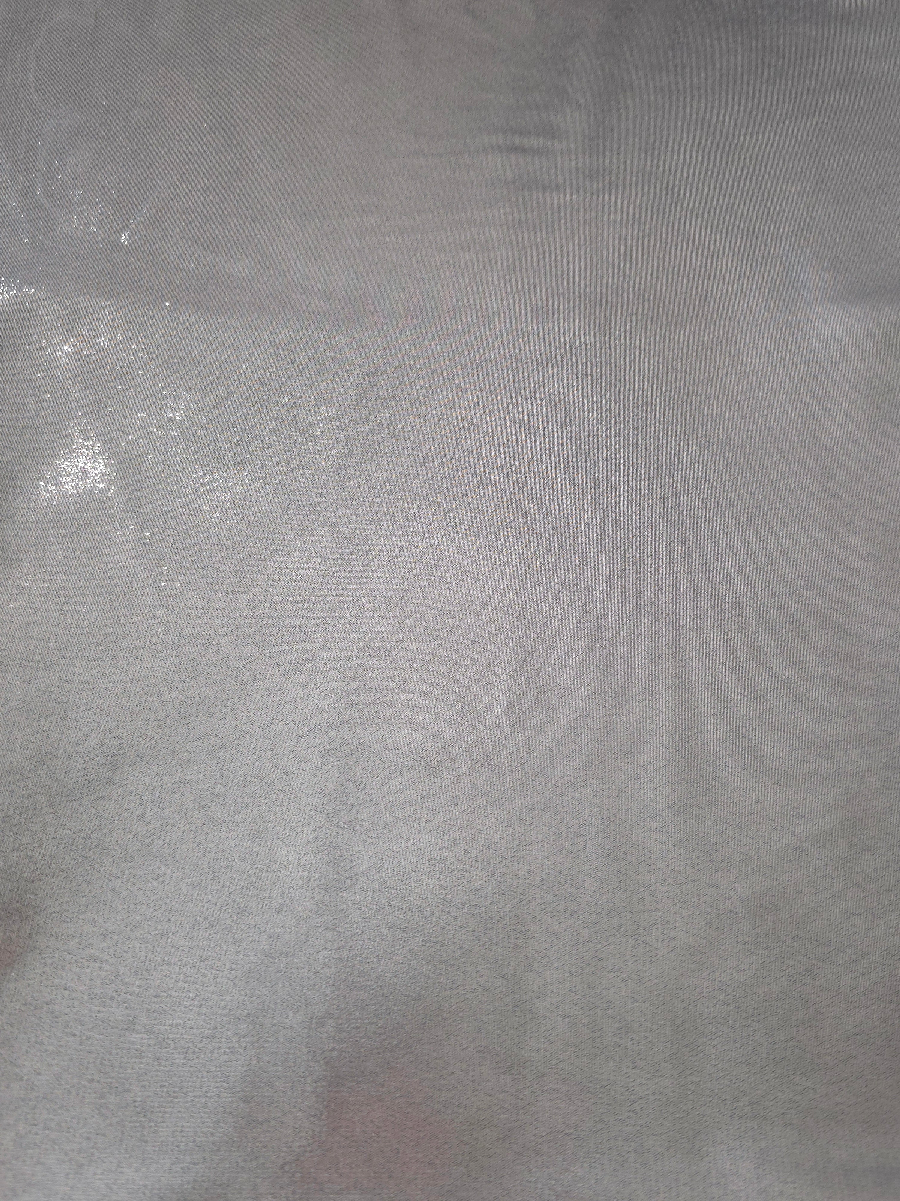Silver gray fabric overview view of liquid metallic shimmer chiffon fabric, highlighting fluid folds and reflective surface