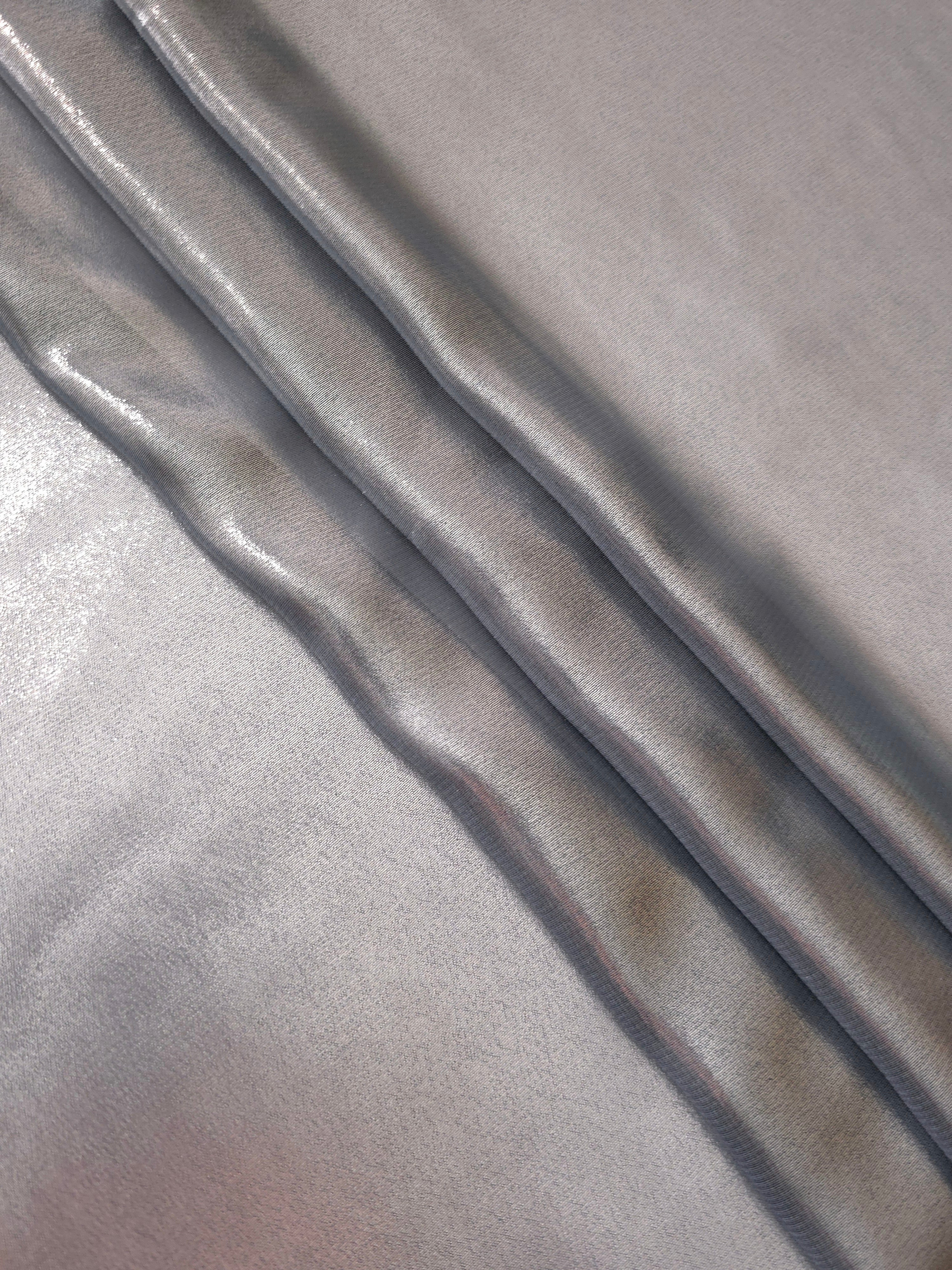 Silver gray flowing folds view of liquid metallic shimmer chiffon fabric, highlighting fluid folds and reflective surface