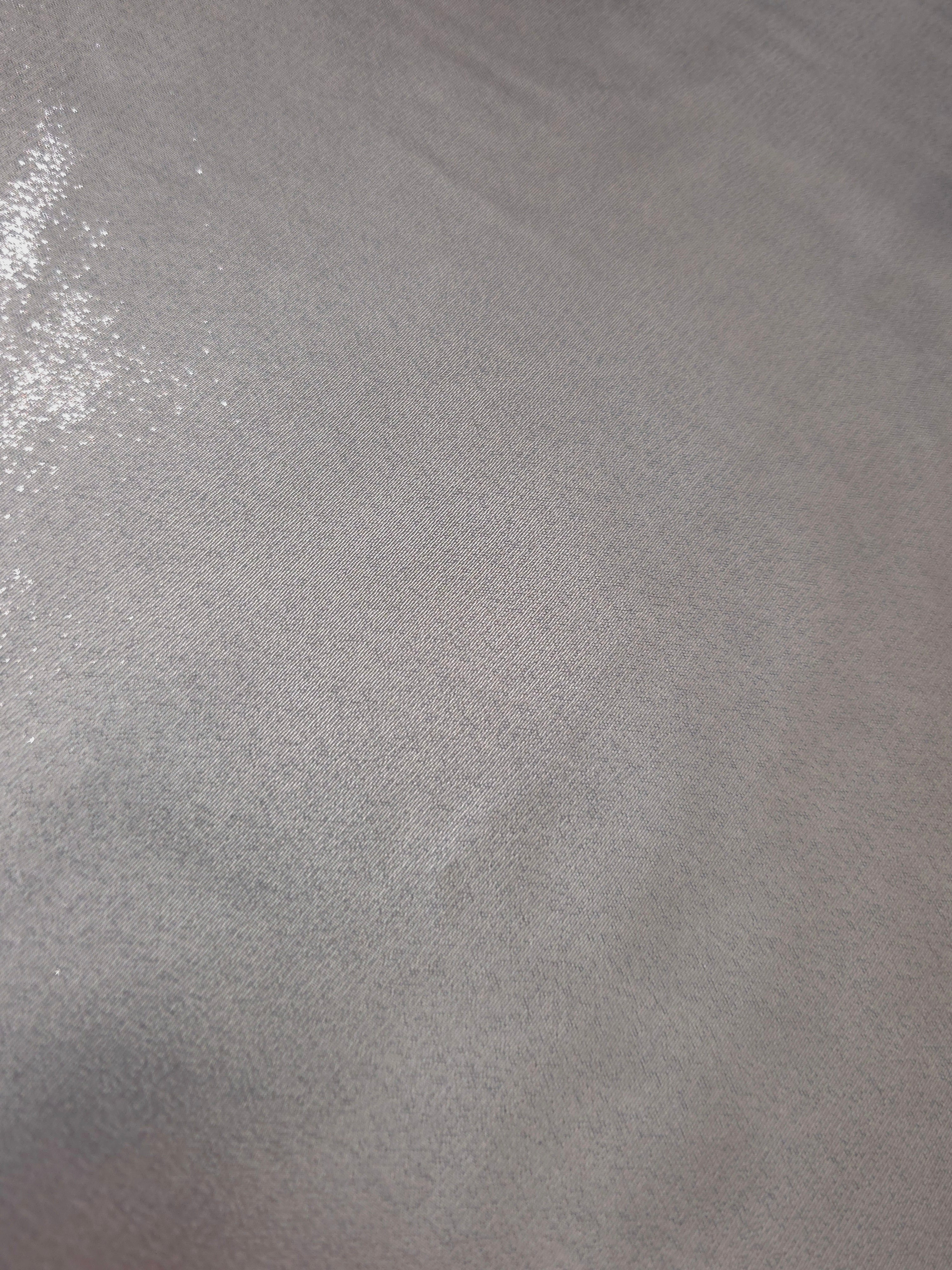 Silver gray fold detail view of liquid metallic shimmer chiffon fabric, highlighting fluid folds and reflective surface