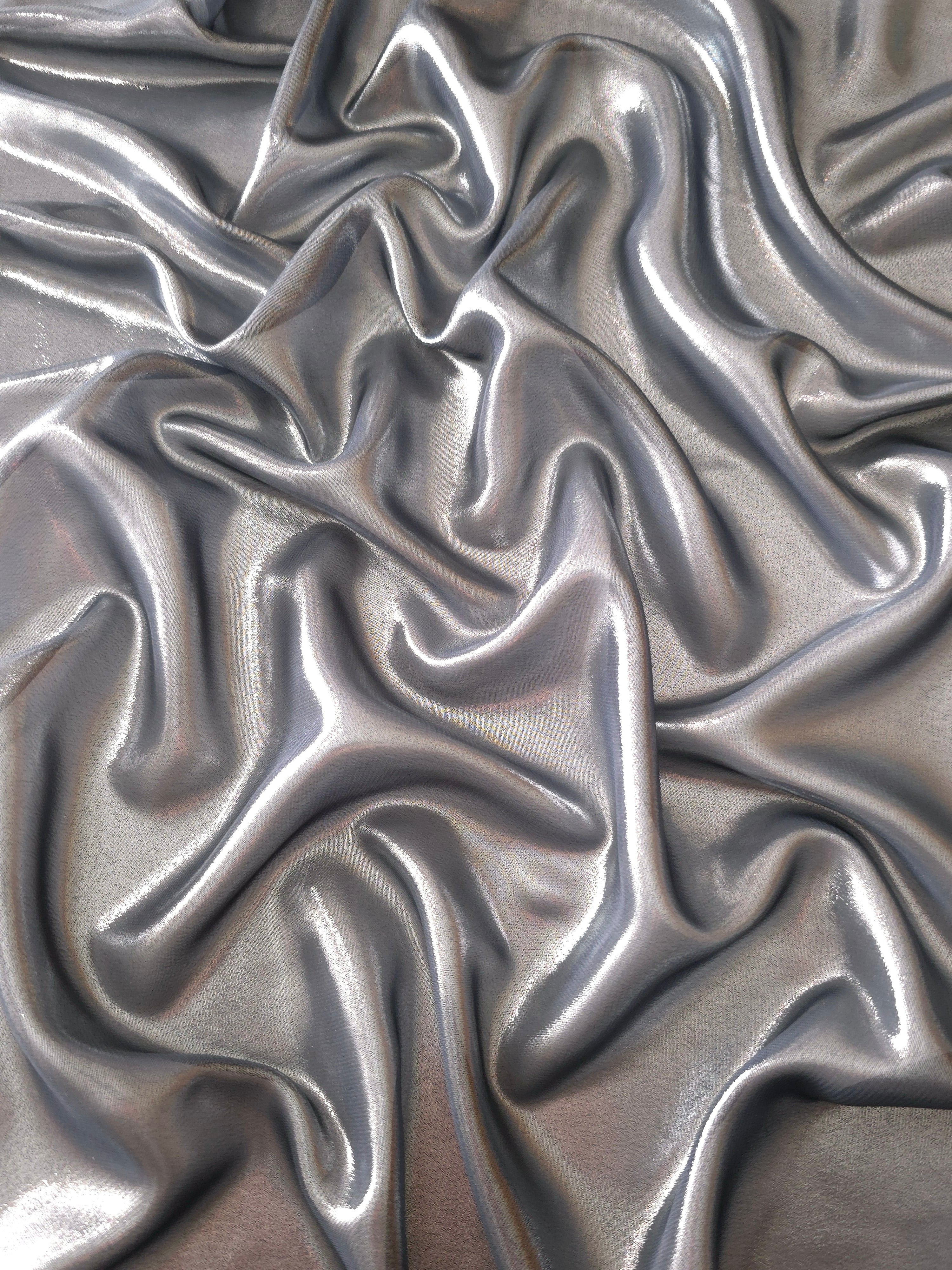 Silver gray surface detail view of liquid metallic shimmer chiffon fabric, highlighting fluid folds and reflective surface