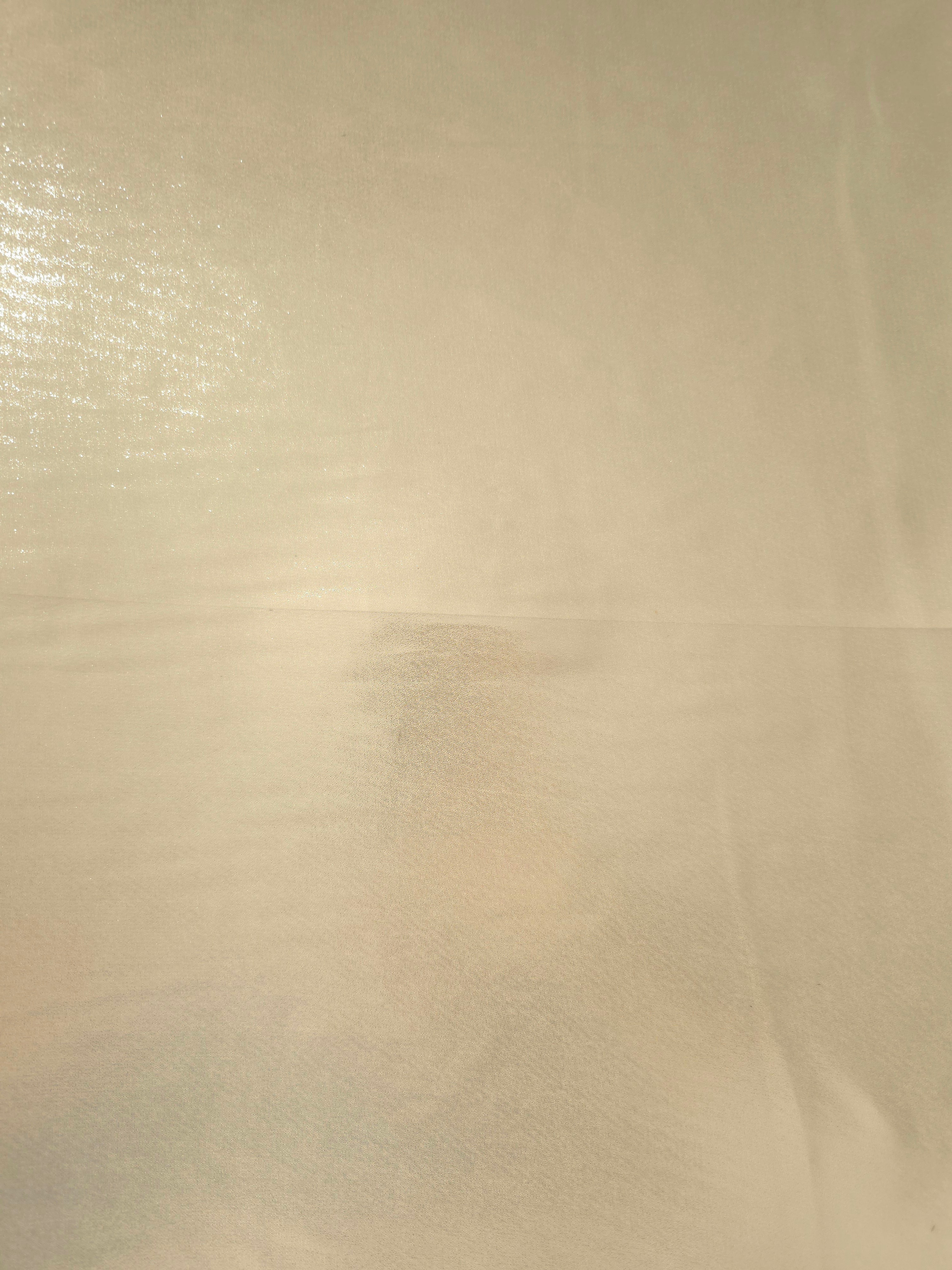 Warm ivory fabric overview of liquid metallic shimmer chiffon fabric, showing lightweight reflective fabric texture and drape
