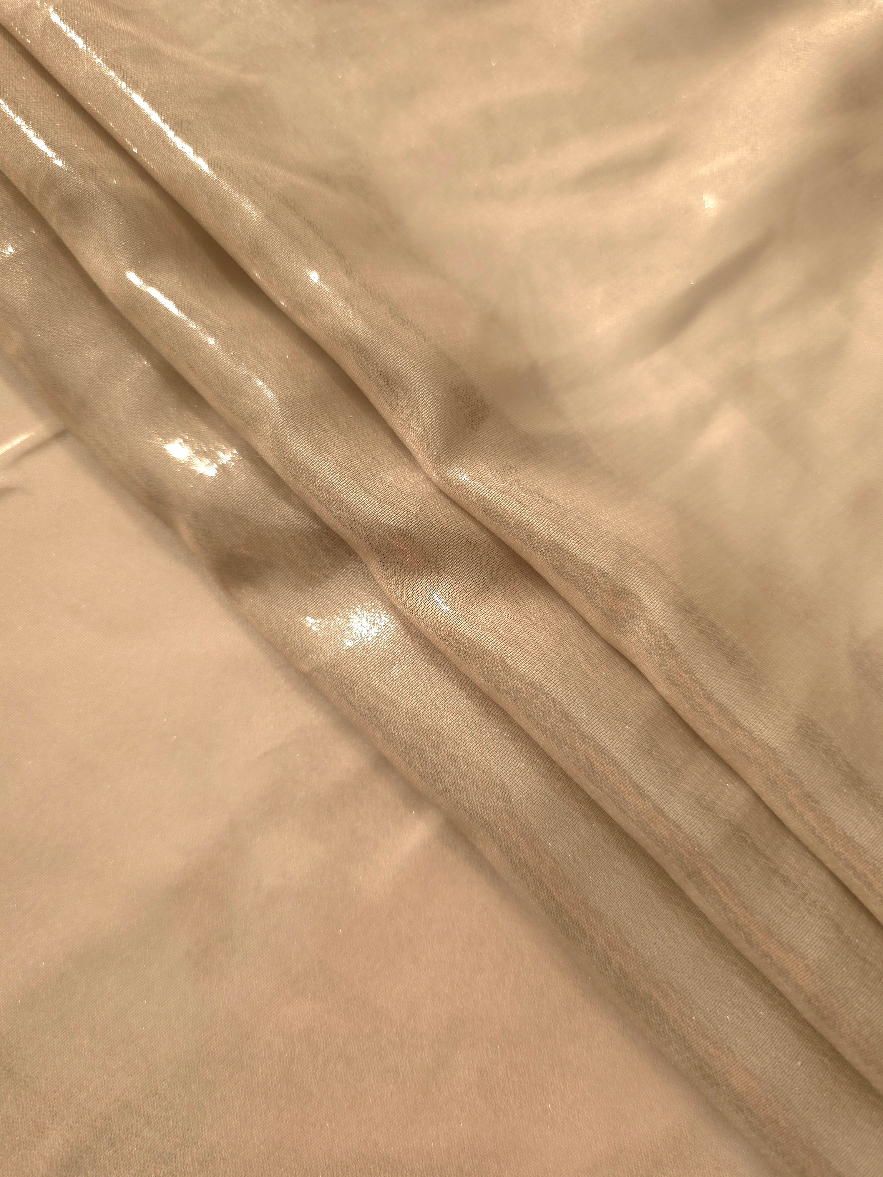 Warm sand flowing folds of liquid metallic shimmer chiffon fabric, showing lightweight reflective fabric texture and drape