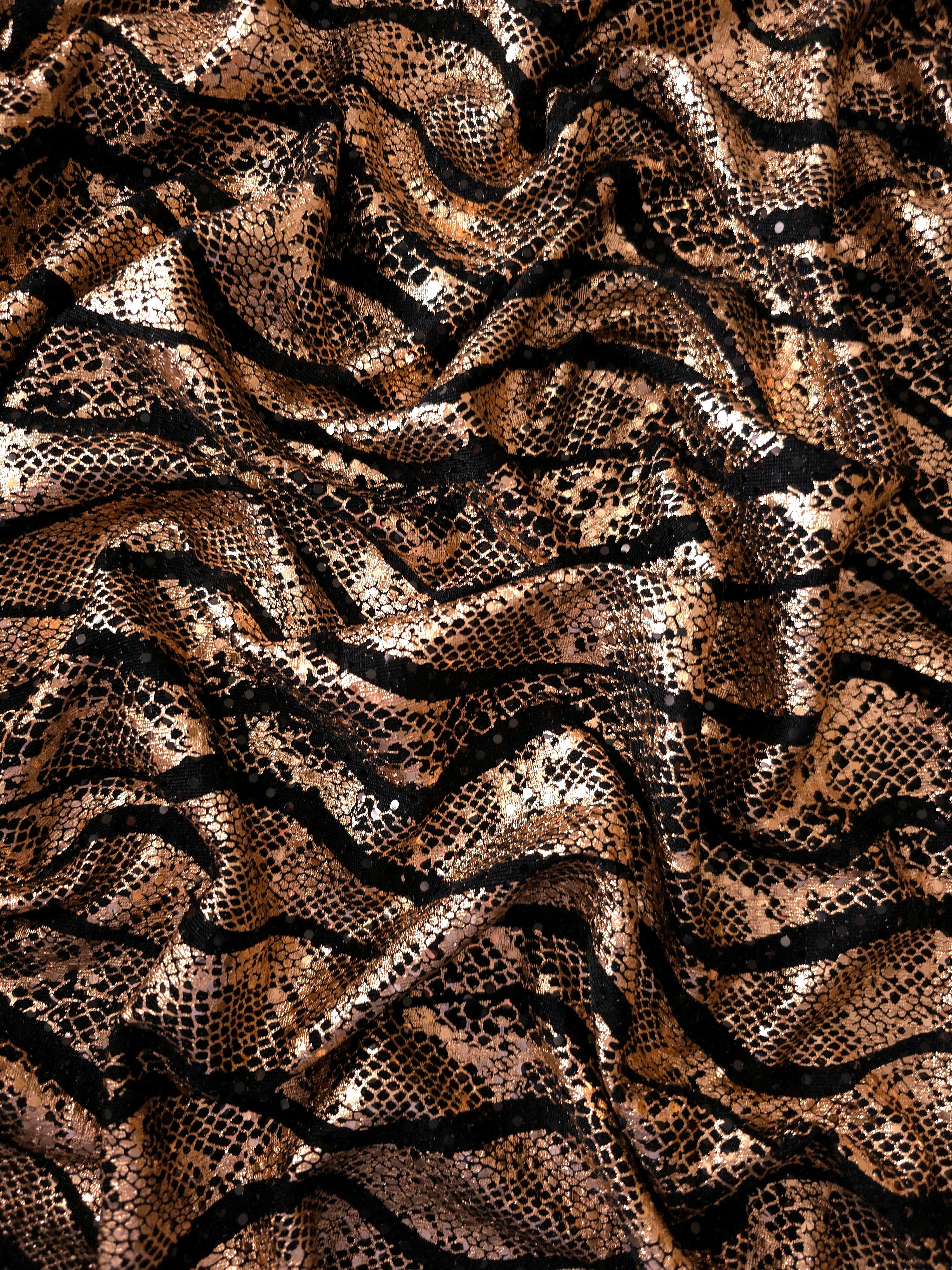 Draped Rose Gold Wavy Python metallic foil sequin fabric on black tulle, showing luminous flow and reflective movement for formal dresses, cape details and performance costumes.