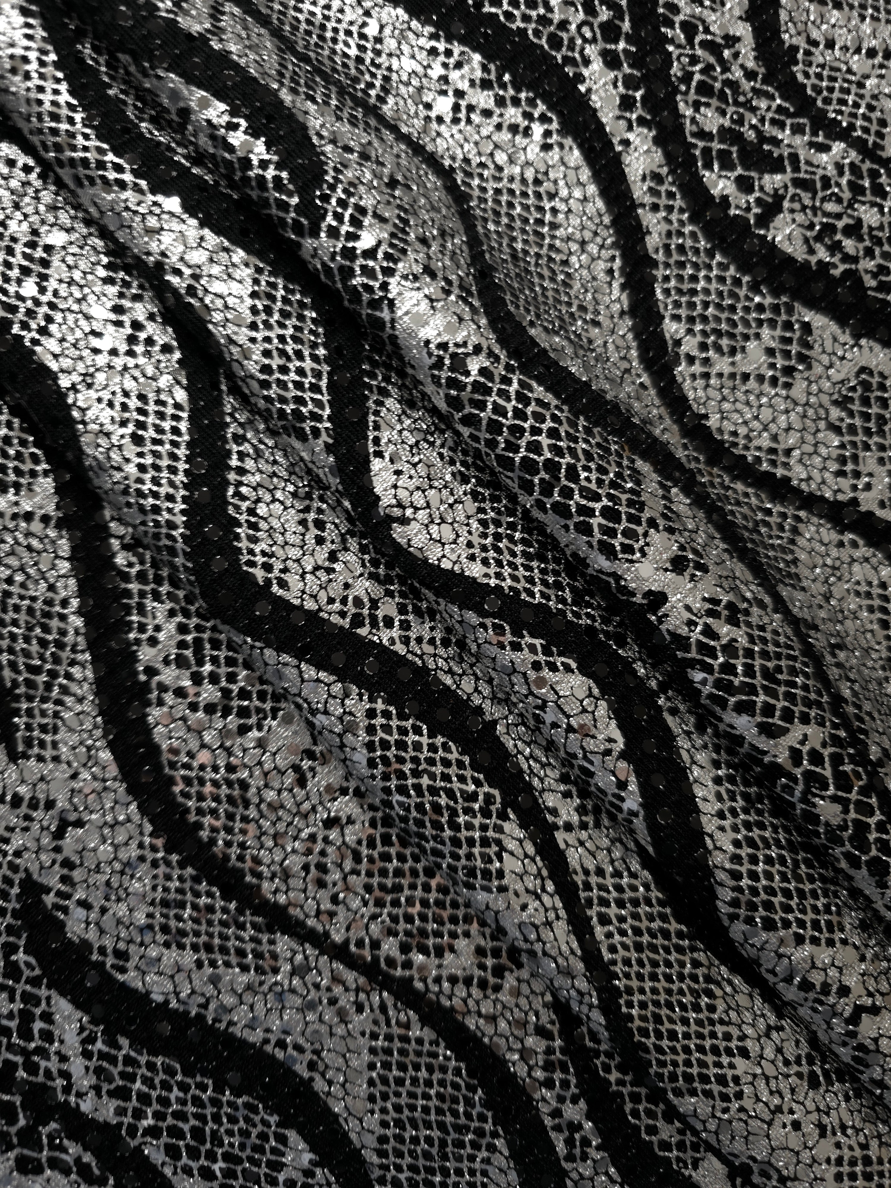 Relaxed folds in Silver Gray Wavy Python sequin tulle reveal reflective metallic patterning over the sheer black base for evening separates, sheer overlays and costume accents.